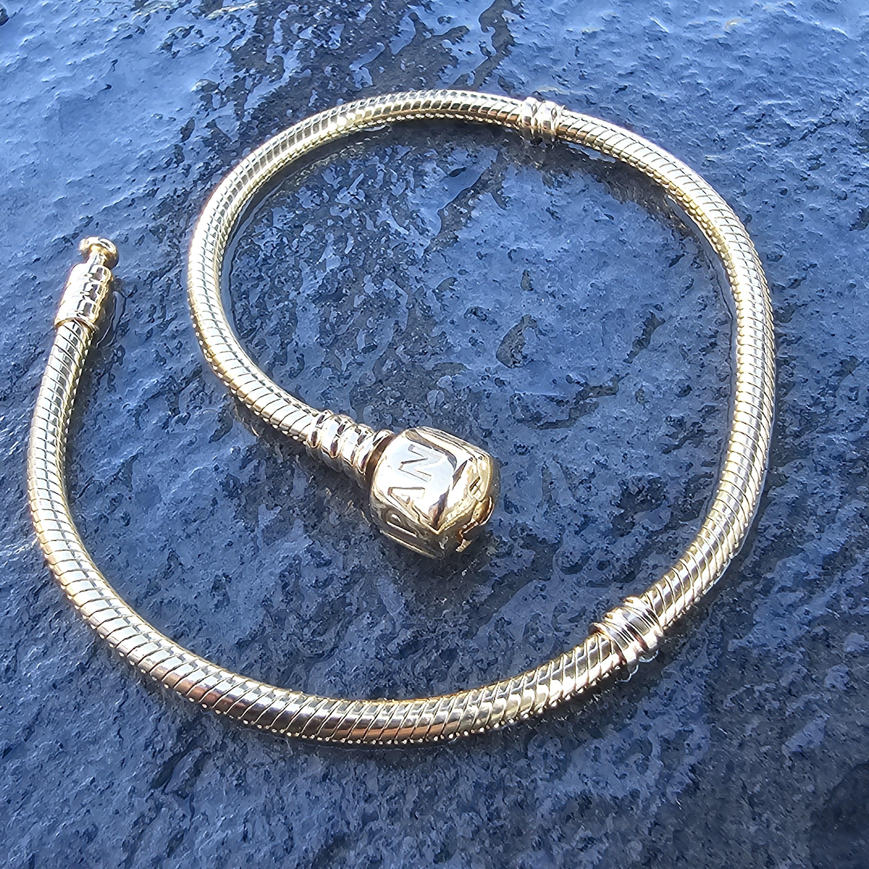 Pandora Charme-Armband 14k Gold.

Dieses exquisite Stück von Pandora ist ein Zeugnis für Eleganz und Handwerkskunst.

Das Armband hat ein schlankes, schlangenförmiges Design aus glänzendem 14-karätigem Gold und einen unverwechselbaren Verschluss mit