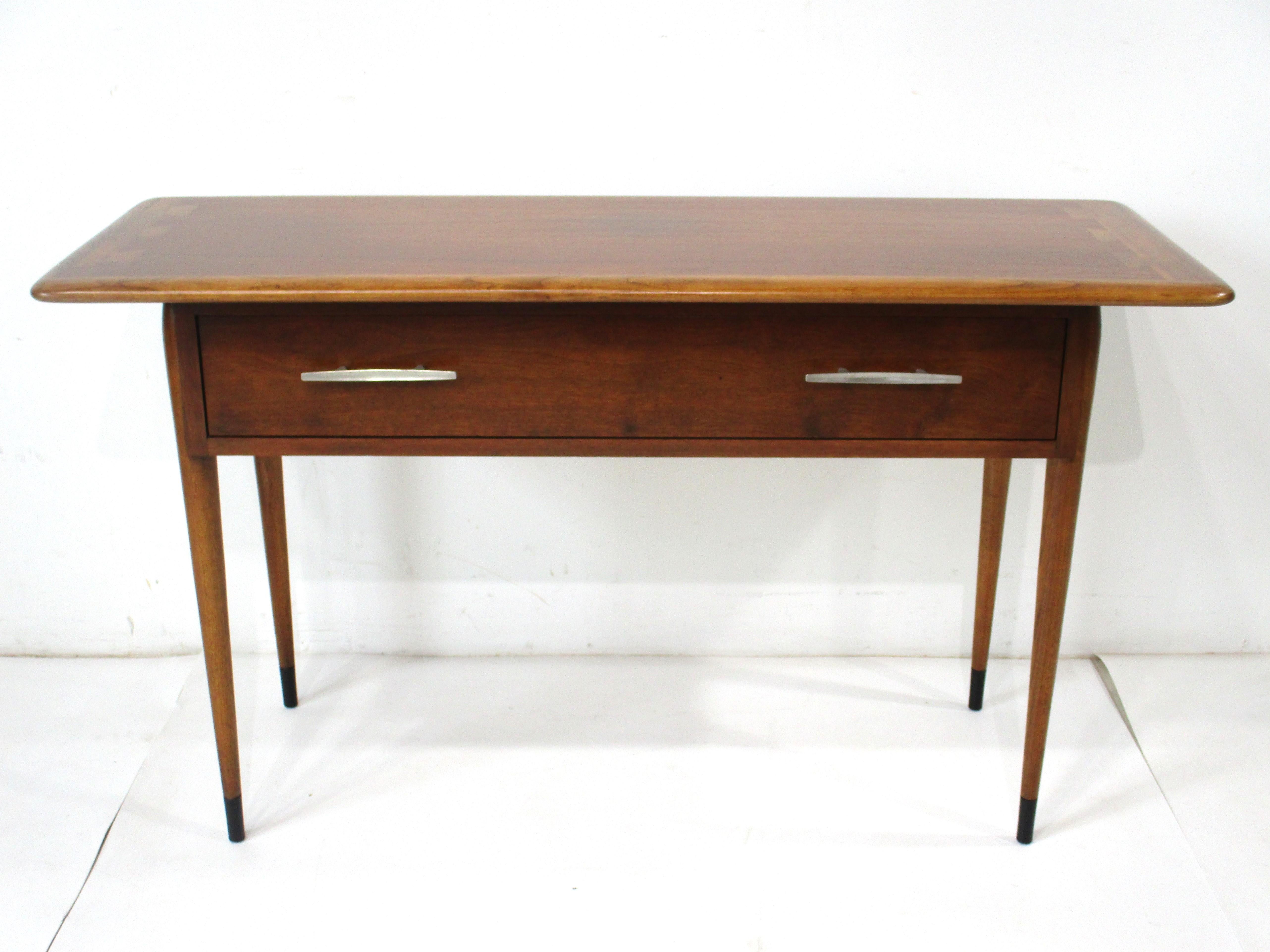  A very well crafted Mid Century walnut console table with one drawer and brushed metal pulls . From the Acclaim collection with their noted dovetailed inlayed detail by designer Andre Bus and manufactured by the Lane Furniture company . This hard