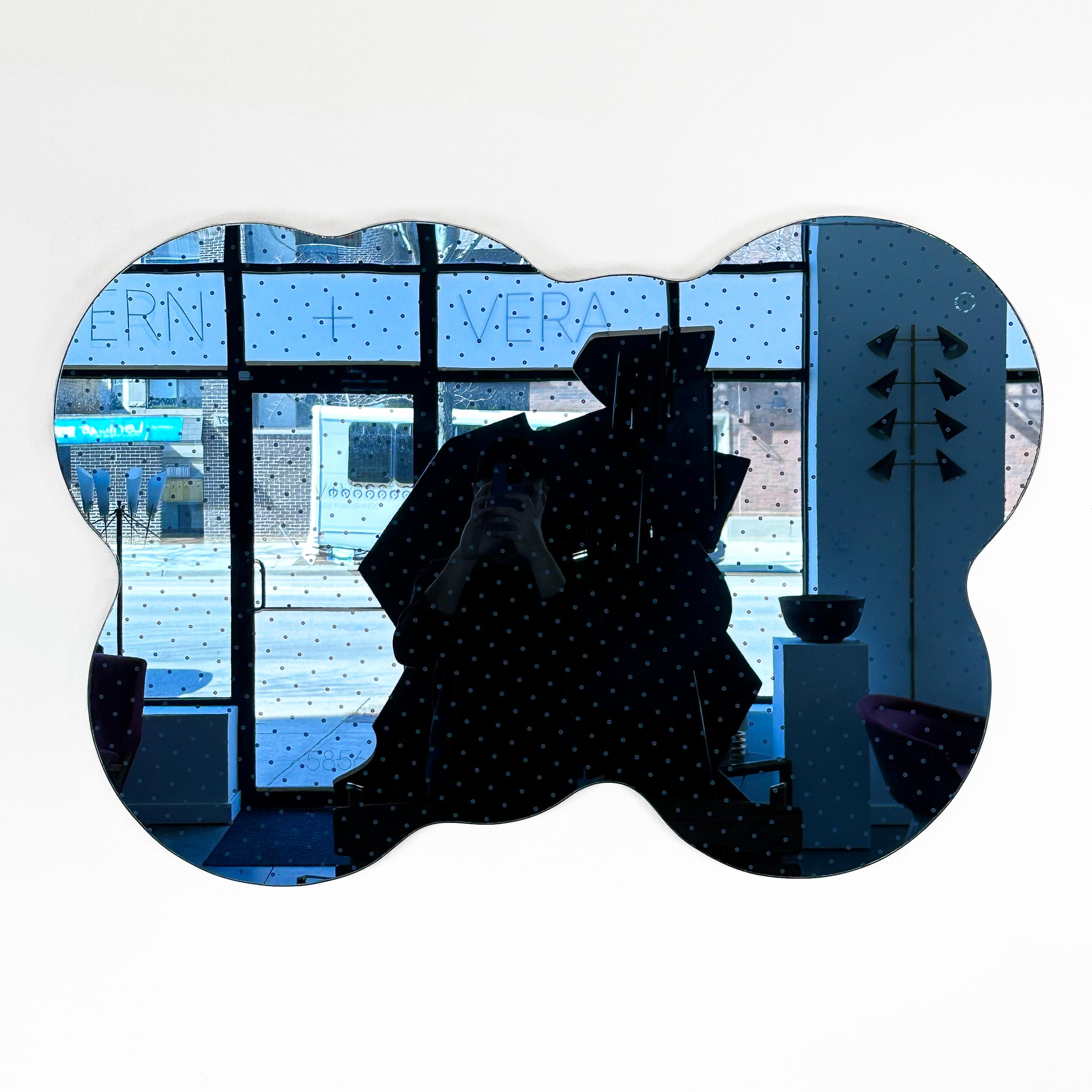 A rare and uncommon Acerbis Morphos blue cloud wall mirror, Italy circa 1980s. This unique modern mirror features an asymmetrical curvaceous cloud shape with an etched diagonal grid of small polka dots as a decorative pattern. Mirrored in a