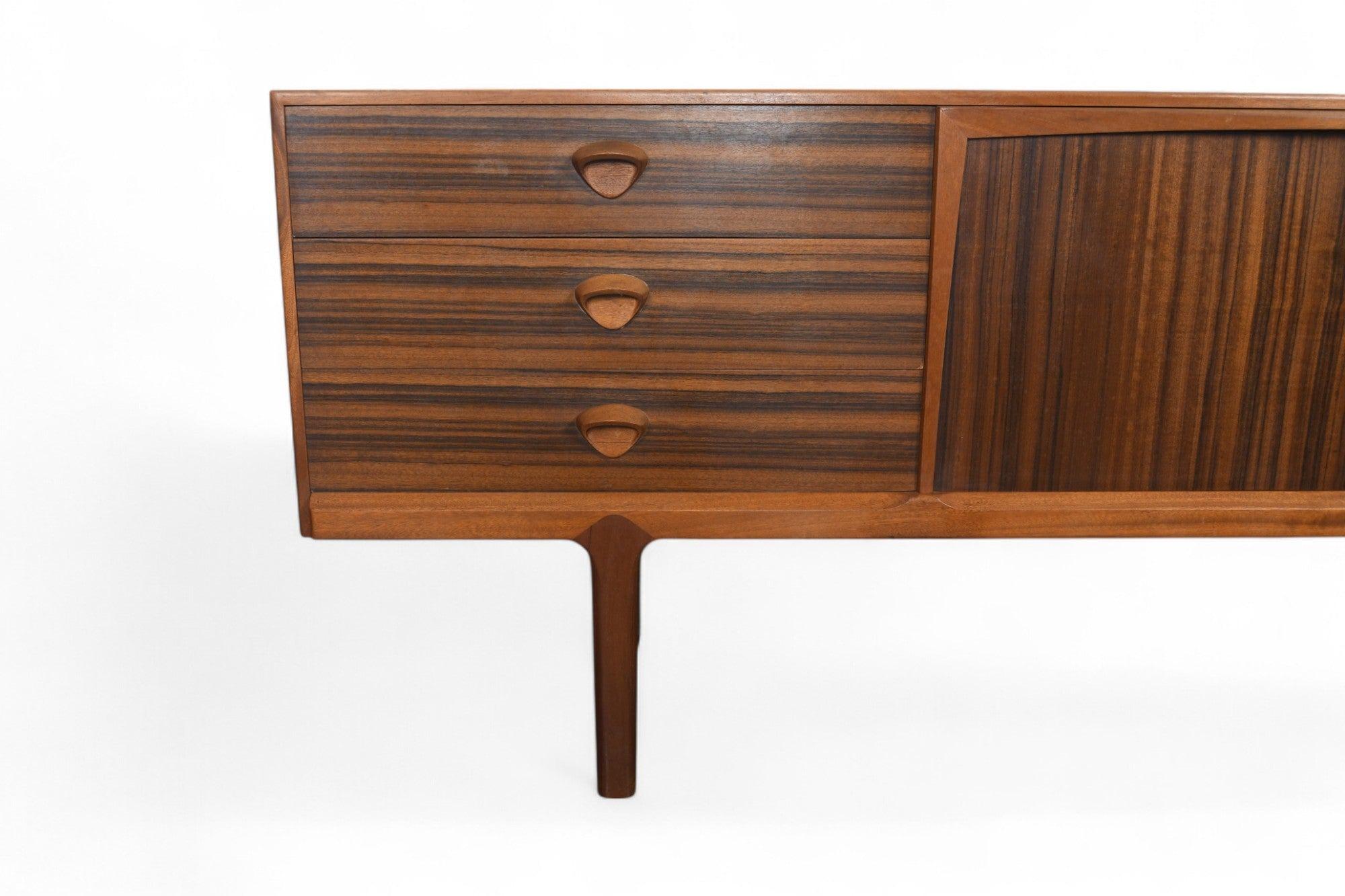 Origine : Écosse
Designer : Val Rossi
Fabricant : A.H. McIntosh
Époque : années 1960
MATERIAL : Noyer, Afromosia
Dimensions : 78.75″ de largeur x 18.5″ de profondeur x 31″ de hauteur