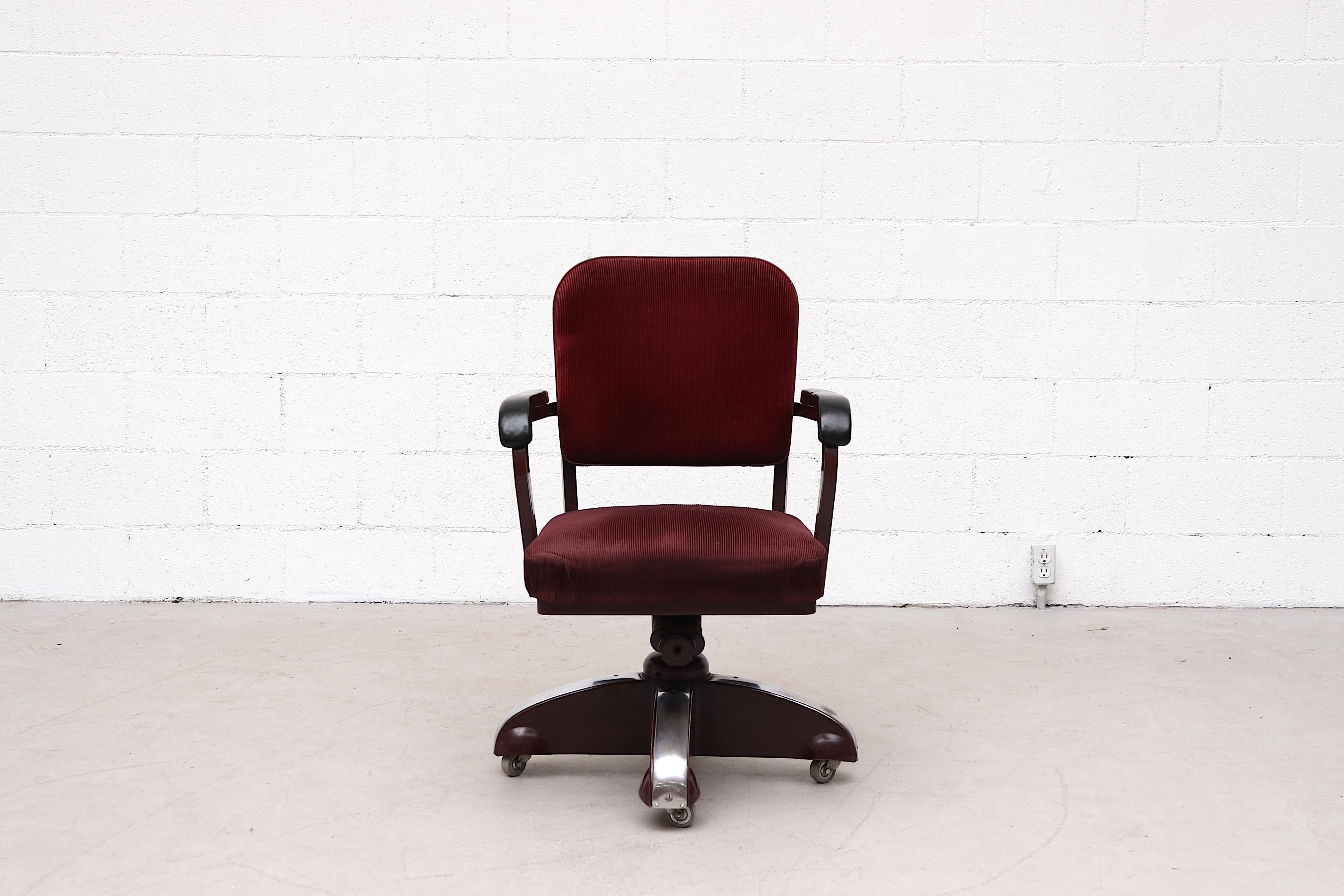 Handsome Ahrend de Cirkel red corduroy rolling office chair with on burgundy enameled meal frame with black leather arm rests and chrome accents. In original condition with moderate wear consistent with age and use.