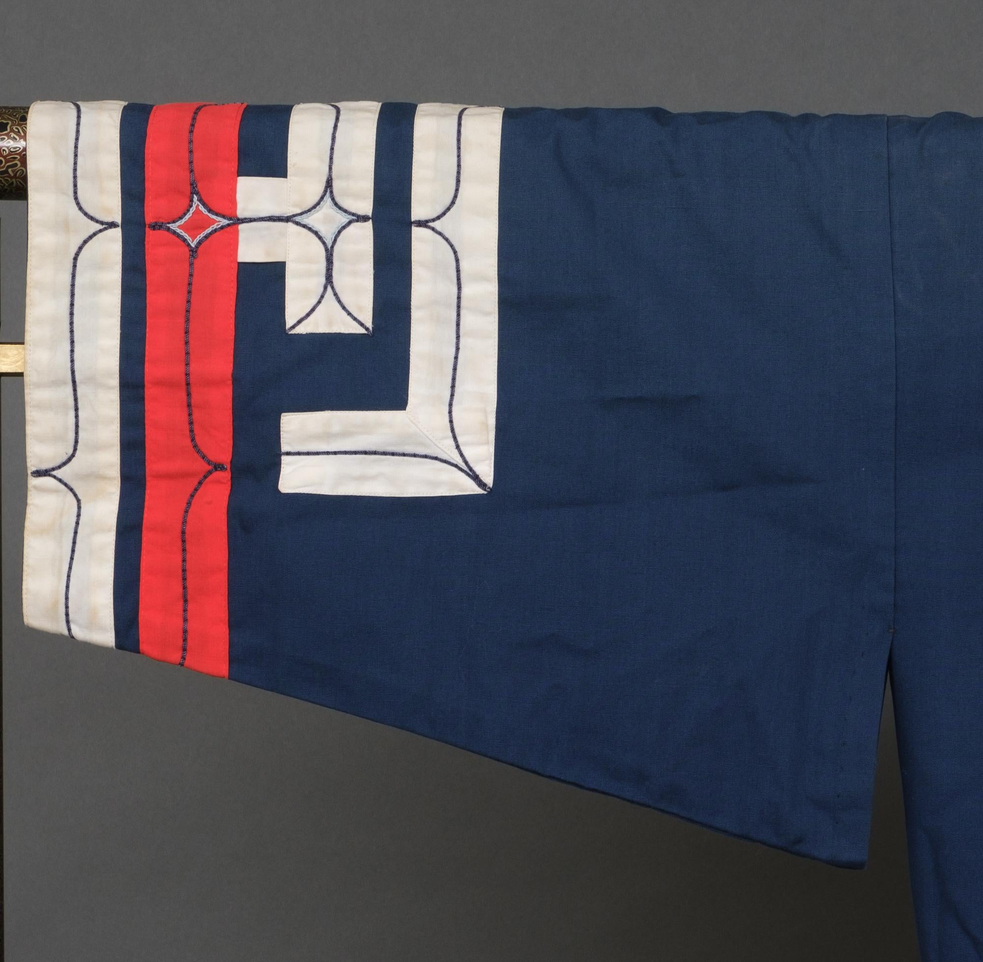 Rare Japanese Ainu navy blue cotton robe featuring wide red and white appliquéd bands along the edges with embroidered geometric shapes.

Acquired from an Ainu education center in the town Shiraoi, Hokkaidô. The last photo shows the lovely visit to