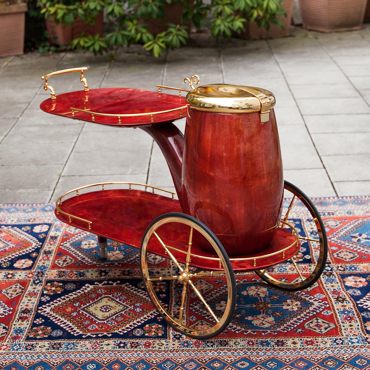 Aldo Tura Barwagen in Form einer Pfeife, lackiert in rotem Ziegenleder mit goldenen Messingapplikationen und einem großen Behälter als Sekt- oder Weinkühler.
In Anlehnung an die Idee von Rene Magritte. 
Einer der bekanntesten Entwürfe von Aldo Tura.