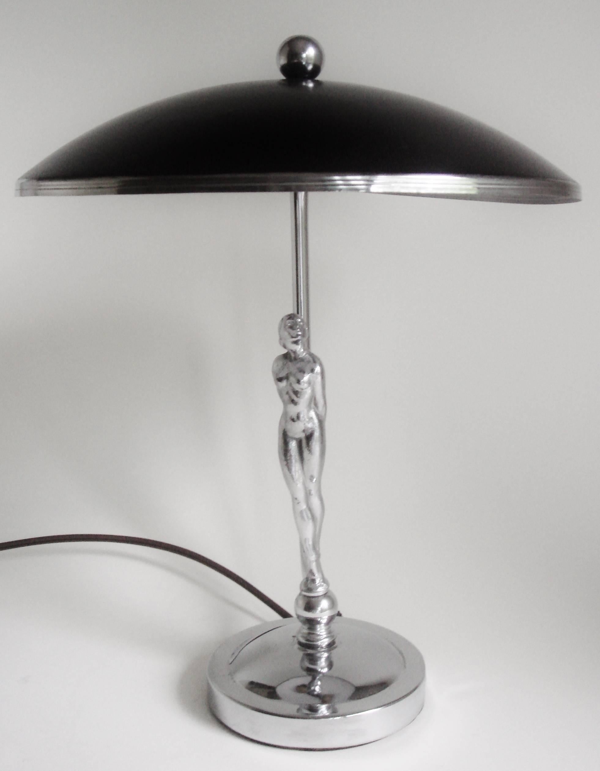 This rare American Art Deco chrome and black enamel shaded desk lamp features a chrome circular stepped cushion base that supports a beautifully sculpted chrome nude female figure standing on a chrome sphere. A chrome tube rises up from the rear of