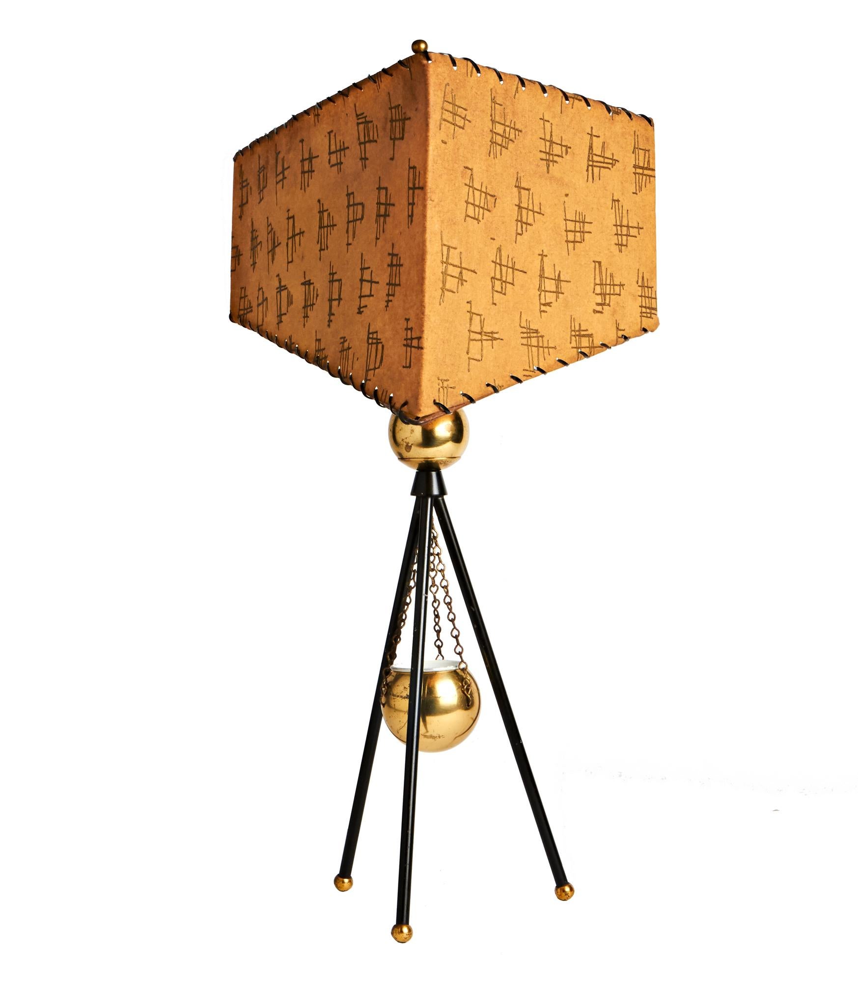 This stunningly designed brass and matte black tripod lamp is by The Majestic Lamp Company. It features a brass globe vase with a white enameled liner suspended on three brass chains from the brass globe mounted at the apex of the tripod. The three