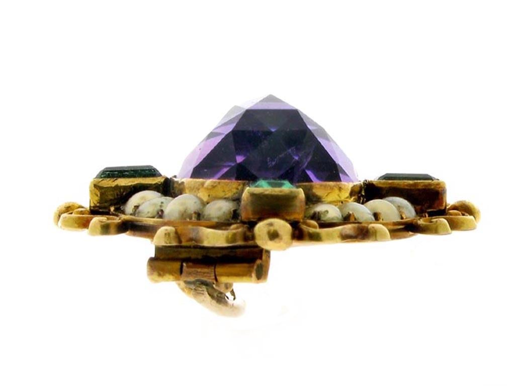 Rare amethyst, emerald and pearl brooch by Carlo Giuliano. Centrally set with an oval rose cut natural unenhanced amethyst in a closed back rubover setting with an approximate weight of 10.00 carats, additionally set to the corners with four