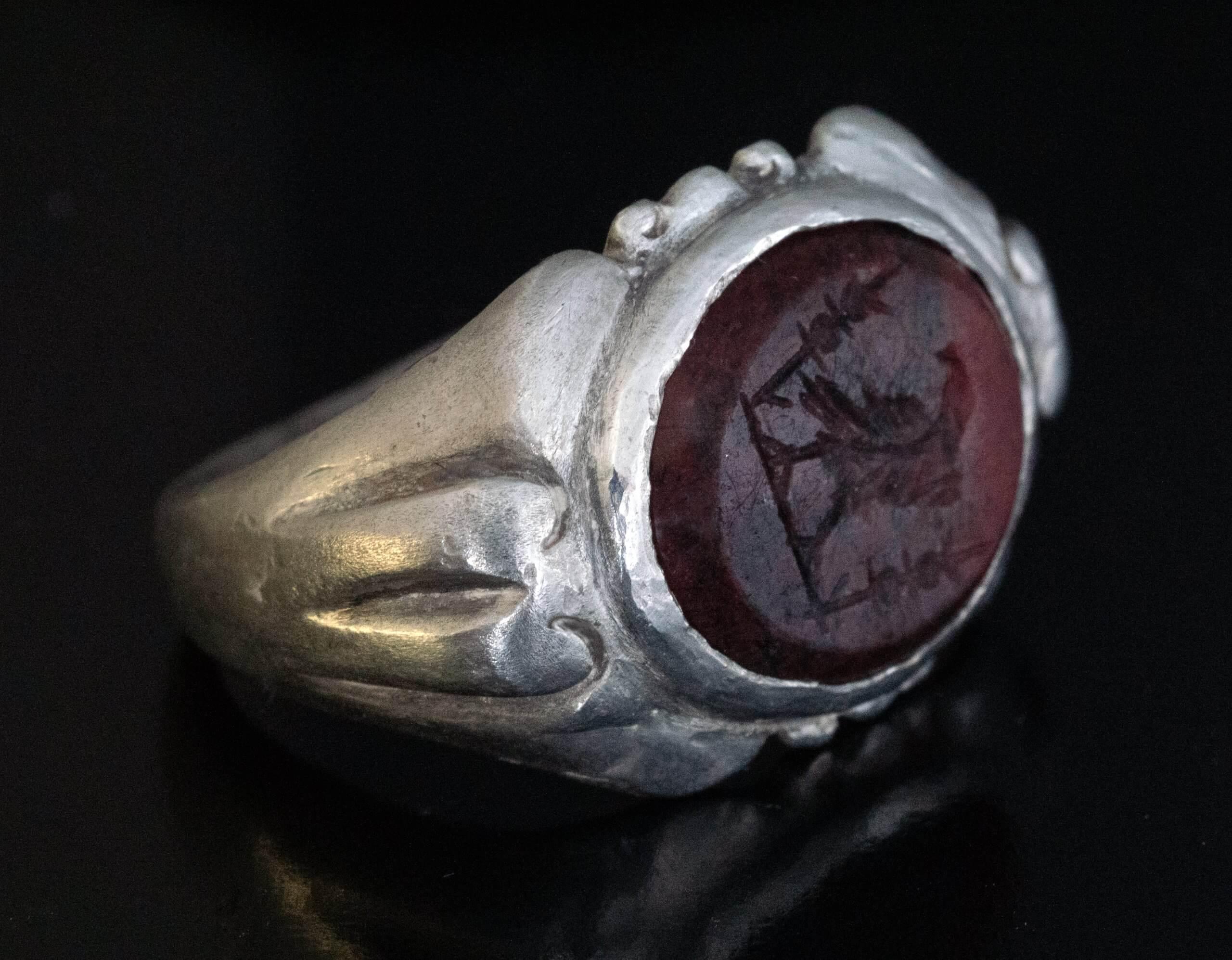 Roman Empire, circa 300 AD.  This rare silver legionary ring features a dark red jasper intaglio finely carved with Roman Imperial eagle standing between two military standards.  The jasper intaglio measures 14 x 12 mm (9/16 x 7/16 in.)  Weight is