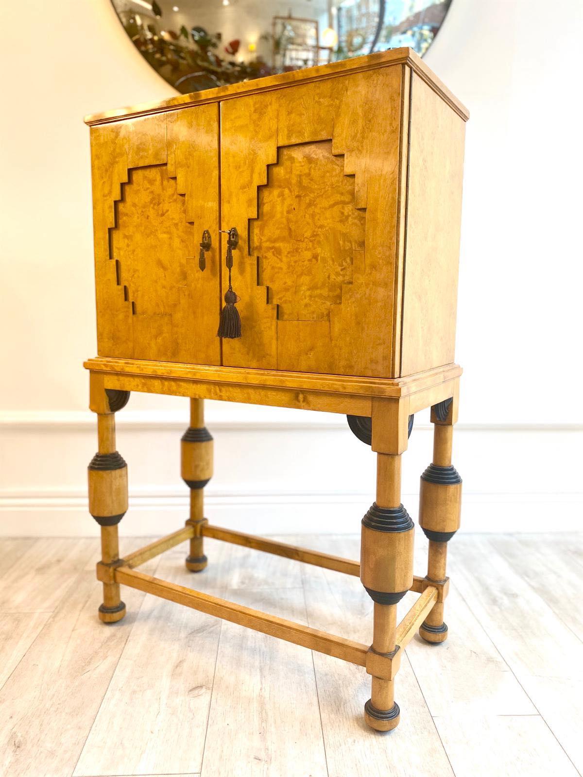 Beautiful and rare 1920s Art Deco cabinet on tall turned legs made from birch and ebonised wood. The body of the cabinet has two doors which incloses 5 drawers with beautiful inlaid detailing and ebonised handles.

Very useful and stylish cabinet