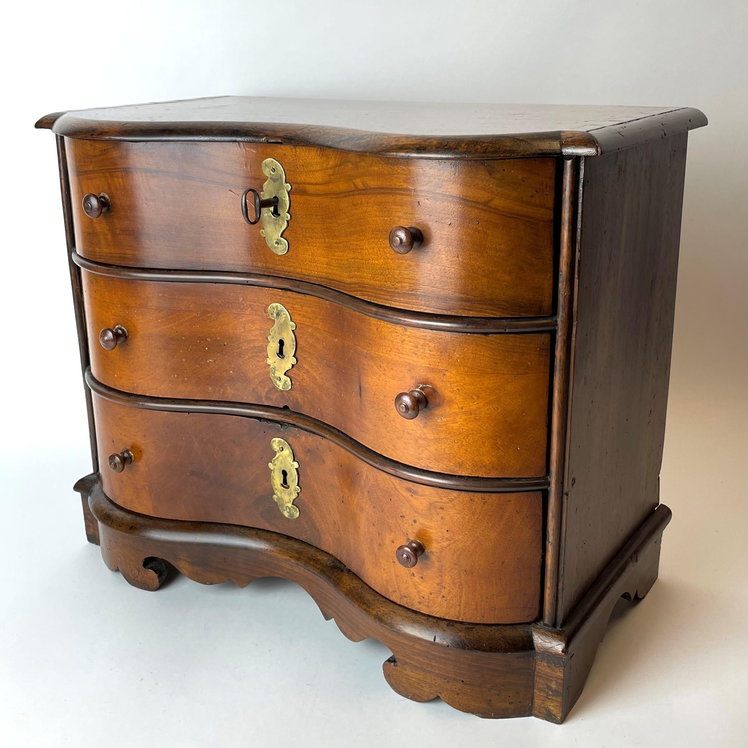 Rather large and rare miniature chest of drawers in late baroque from the early 18th century. Made in Walnut with key-plate in brass. All the drawers in the dresser with original locks and with fantastic original furnishings in marbled