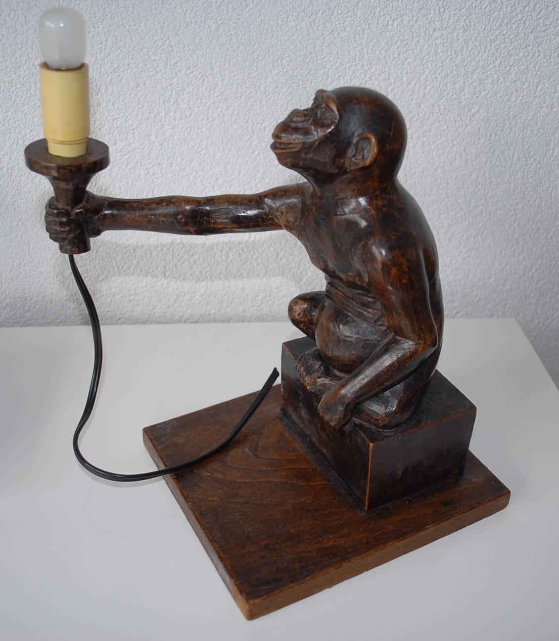 This monkey is looking for a new home!

Great antique, hand-carved monkey offering you his lamp. If you look closely than you can see him reaching out and offering the lamp to you, with a slight grin. This rare and delightful chimpansee desk or