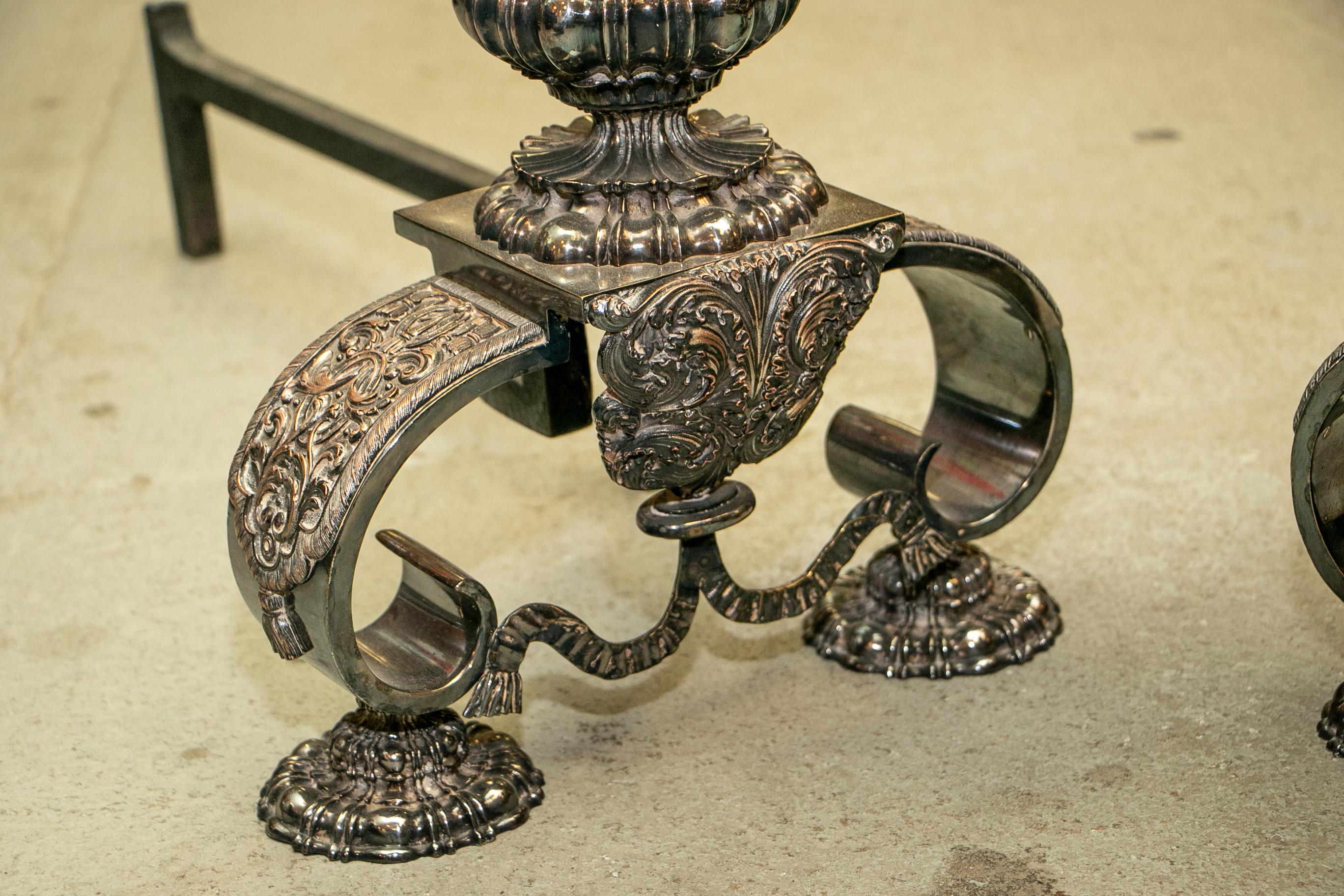 La paire de chenets néoclassiques vasiformes en bronze argenté avec de hauts fleurons en forme d'artichauts, vers 1910-1920. Relief global en forme d'œuf et de fléchette sur le sommet et la base bulbeux. Des motifs de bouclier décorent la partie
