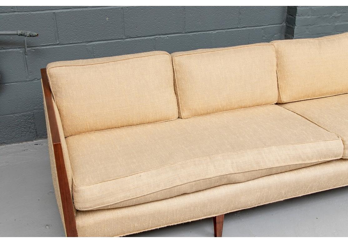 A phenomenal mid century wood framed sofa originally purchased from John Stuart in New York City in 1959. Elegant frame with slightly angled arms ending in one piece with the legs- square tapering in front and square splayed in back. Upholstered