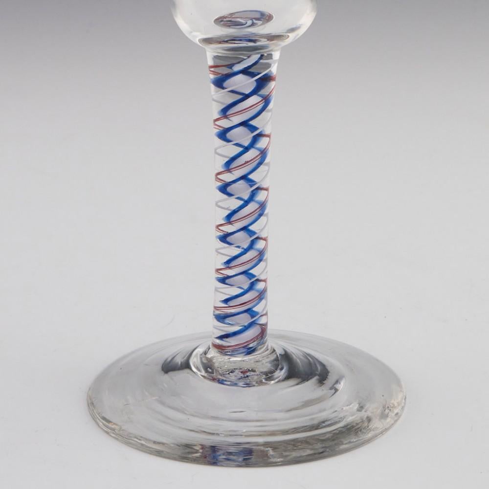 Heading : Rare colour twist Georgian wine glass
Period : George II / George III c1765
Origin : England
Colour : Clear
Bowl : Large bell
Stem : A white enamel thread alongside a two-ply red spiral tape outwith a blue edged multi-ply corkscrew.
Foot :