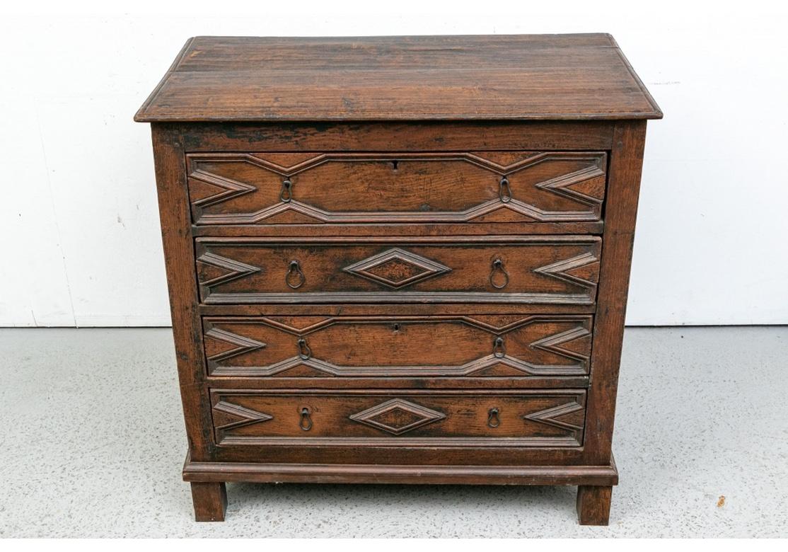An early chest, believed to be English in origin and dating to the Mid-18th Century. The top constructed of two panels with dowels and a carved edge. With elaborately carved drawers- the top and middle ones with angular moldings with V shaped ends