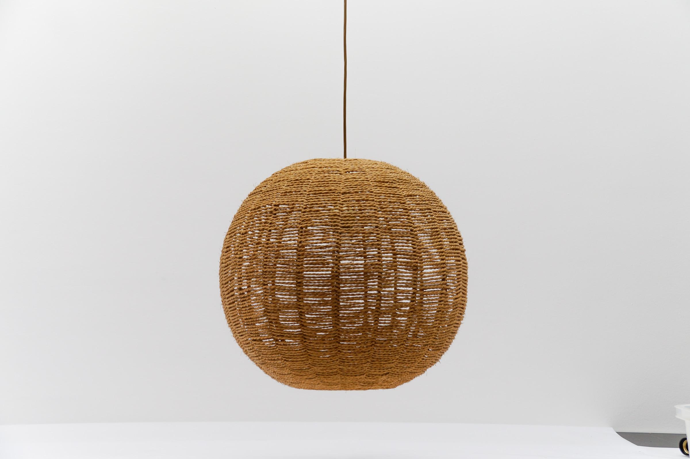 Huge and rare decorative Mid-Century Modern pendant lamp. Designed and manufactured probably in Scandinavia, 1960s.

The lamp can be adjusted from 65cm to a height of 105cm.

Executed in rattan and wood, the pendant lamp comes with 1 x E27 / E26