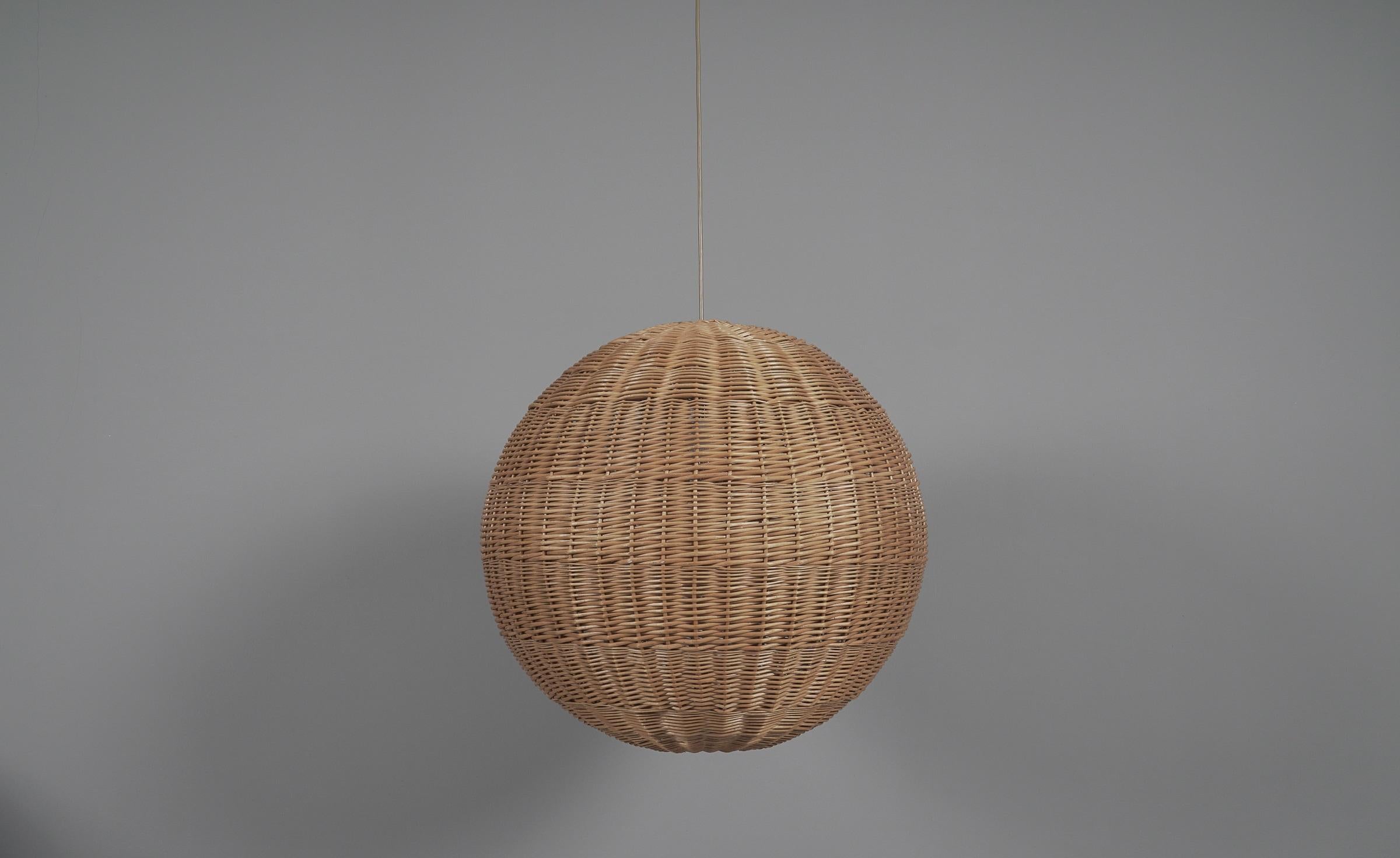 Huge and rare decorative Mid-Century Modern pendant lamp. Designed and manufactured probably in Scandinavia, 1960s.

The lamp can be adjusted from 80cm to a height of 185cm.

Executed in rattan and wood, the pendant lamp comes with 1 x E27 / E26