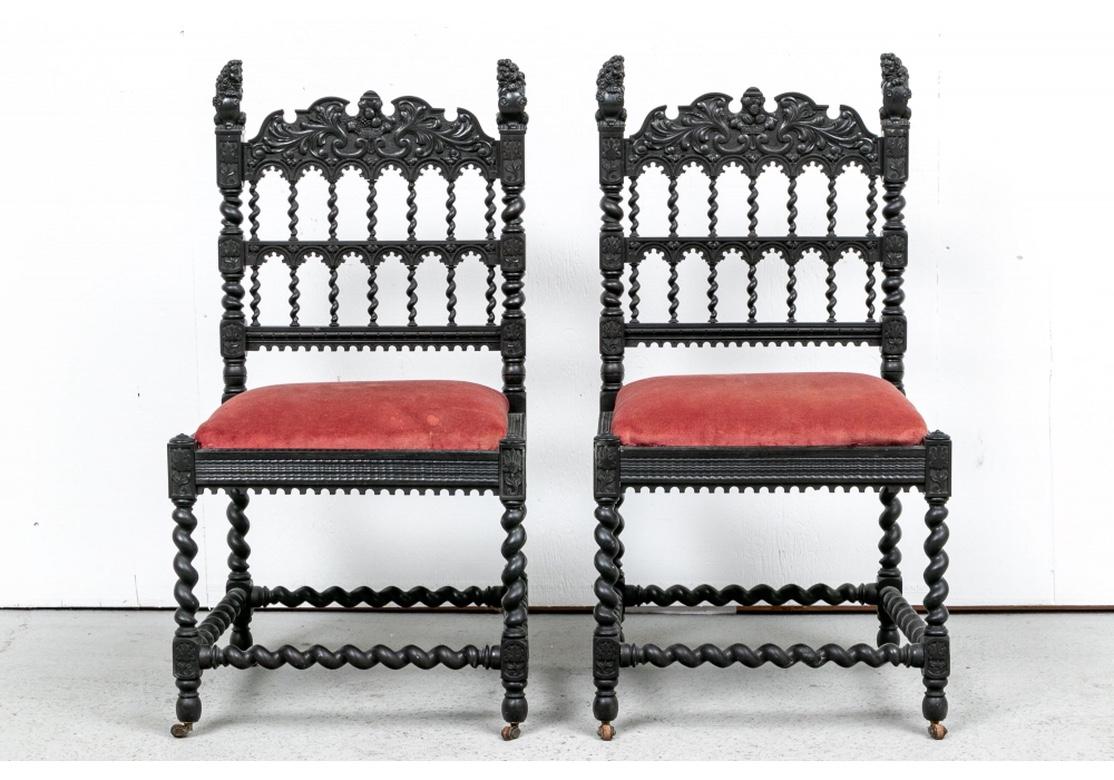 The ebonized chairs with shaped and carved crest rails with leaves and center fruit basket motifs. The barley twist side supports with carved flowers at intervals and standing lions holding shields as finials. The openwork backs with two tiers of