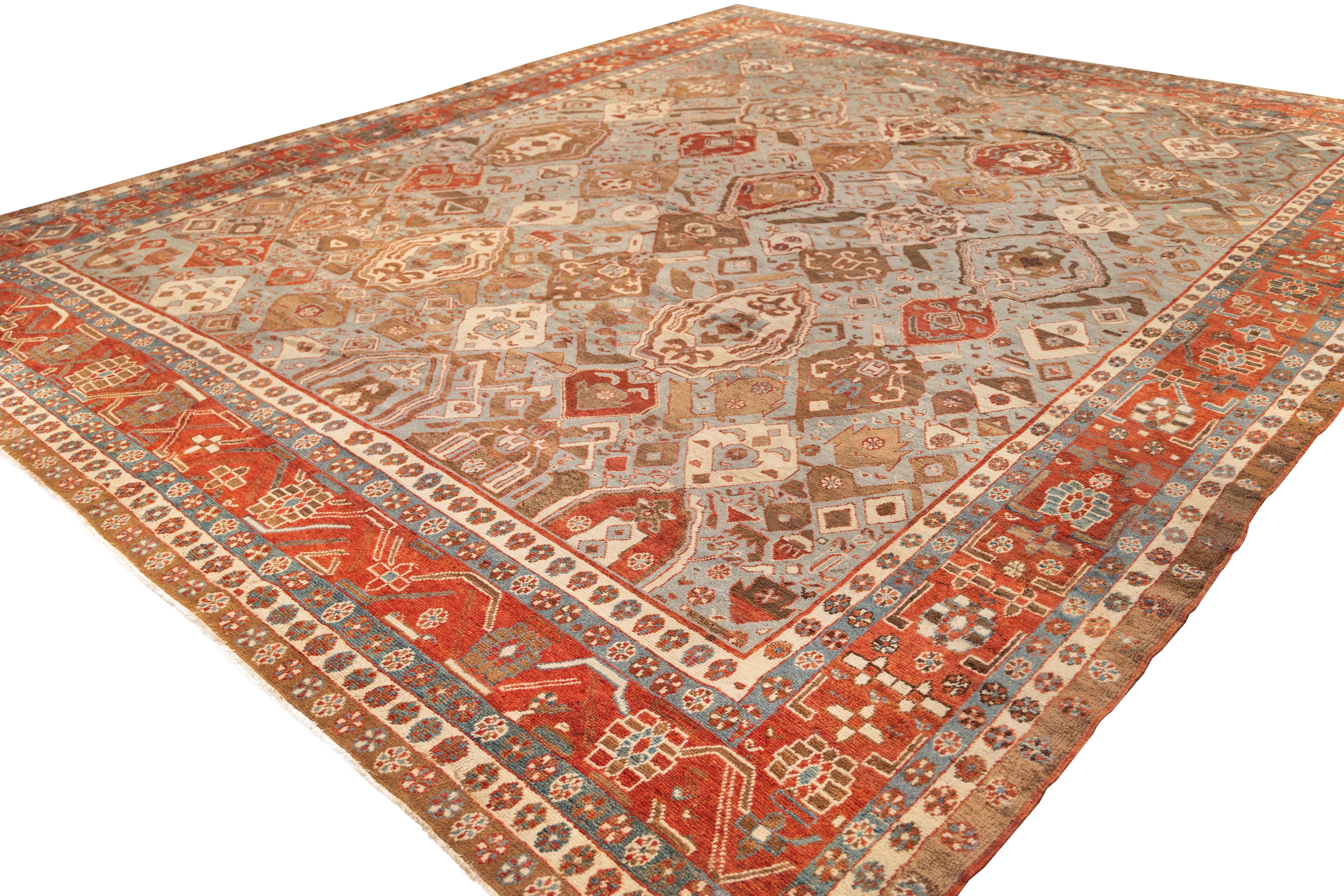 Large Bakhshayesh rug with an expansive field of scattered shields and tribal motifs in a spacious, asymmetric layout. Earthy rust, sand, and ivory tones unfold over a cool, oxidized blue-green background, framed by a wide brick-red border filled