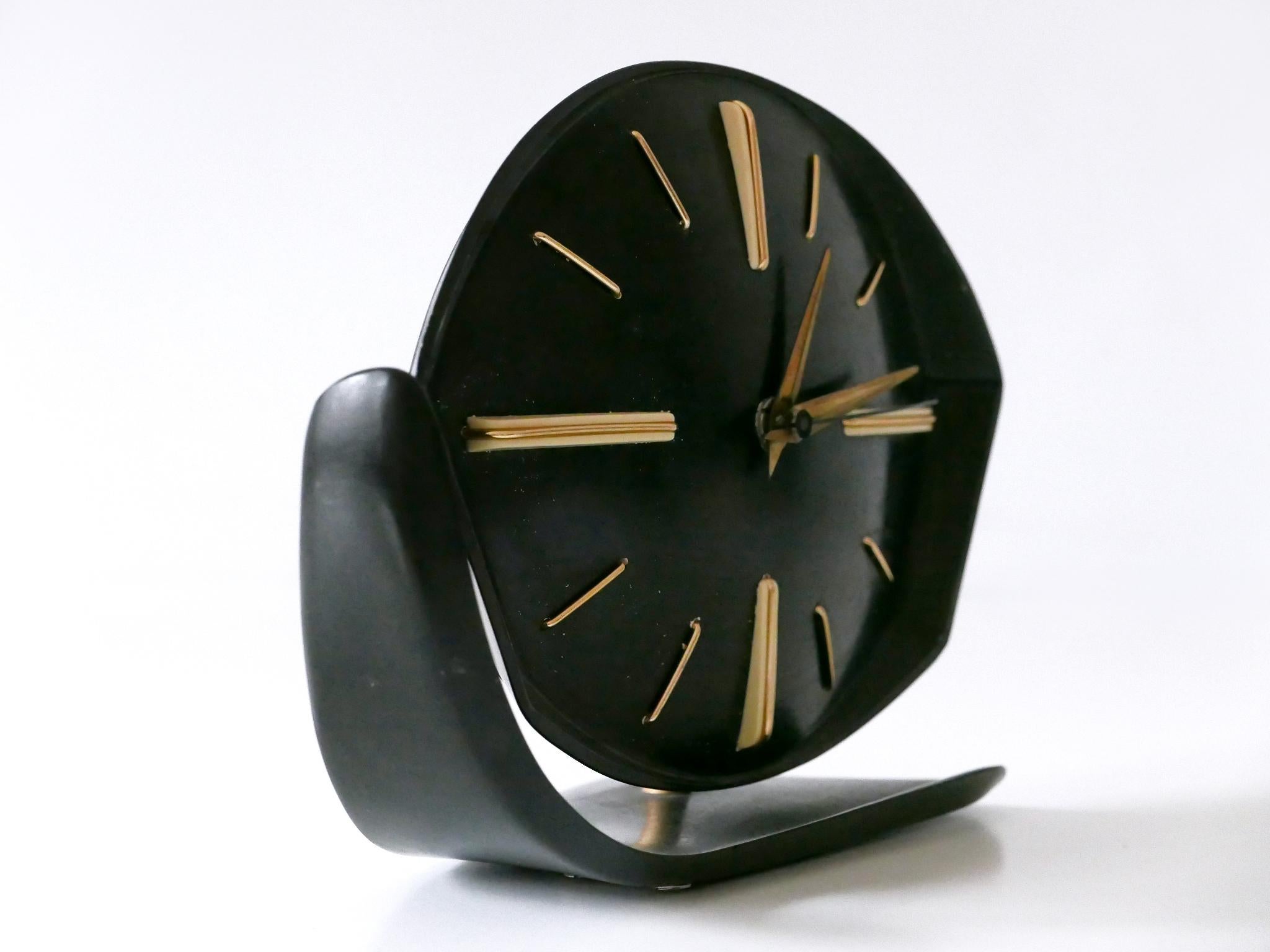 Rare and highly decorative Mid-Century Modern table or wall clock. Rotating body due to brass joint ball. Designed and manufactured by PRIM clocks, Czech Republic, 1950s.

Executed in black bakelite and and brass.

Measurements:
Height: 7.49 in (19