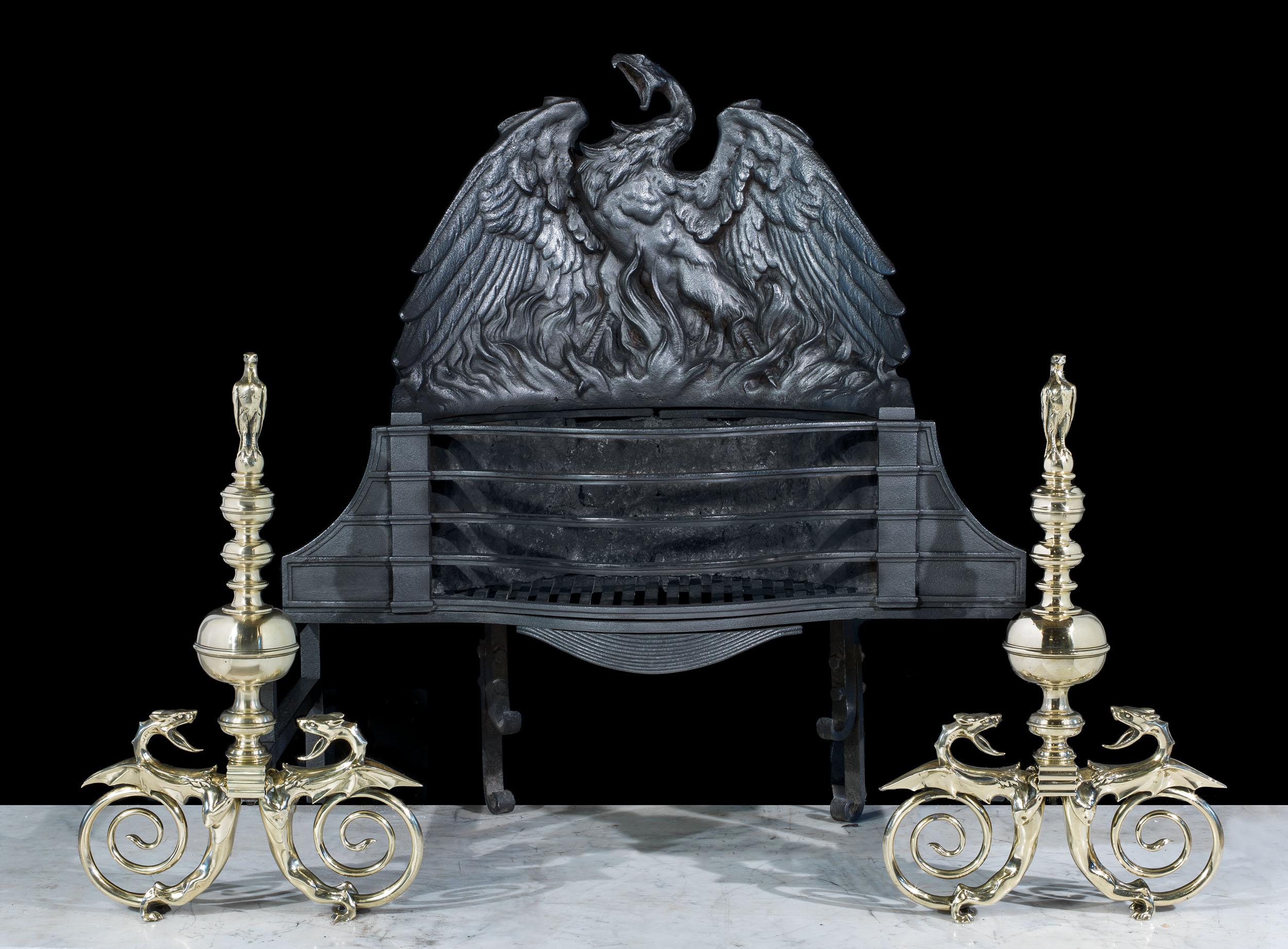A rare and majestic fire basket, depicting a phoenix rising from the flames. The phoenix fire back is mounted above a large four barred grate, which rests on brass andirons. The andirons are surmounted by eagles, and the sinuous feet form winged