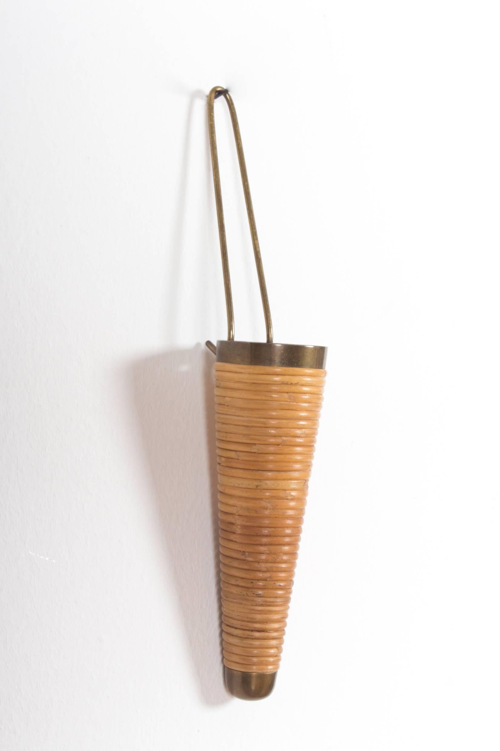 On offer is a highly rare Auböck piece: A small wall vase by Carl Auböck with interesting and intelligent design. 

Brass, partly covered with wicker, circa 1950. 
Marked on the back rim with 