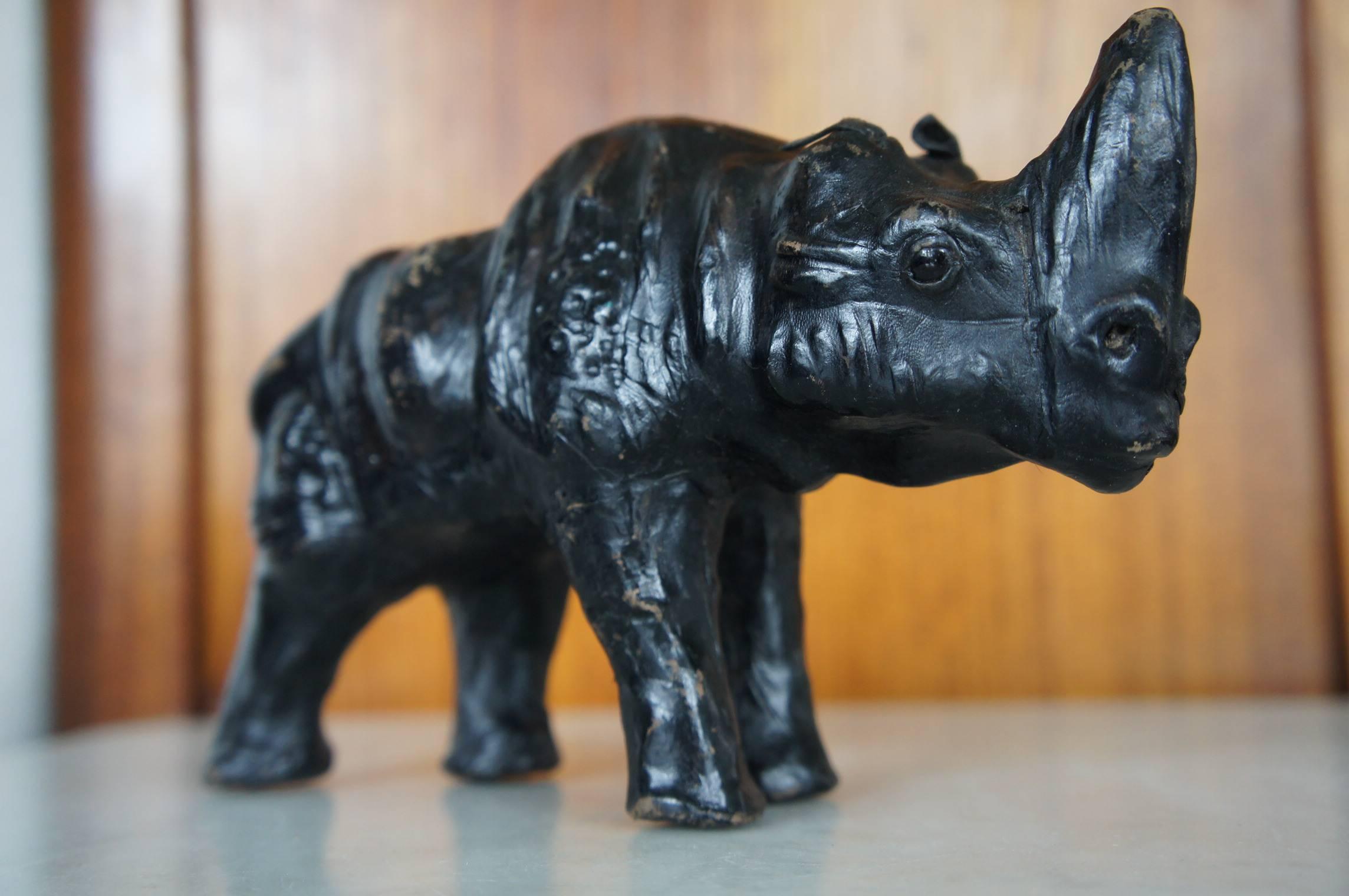 Midcentury pair of handcrafted black rhinos.

These 20th century wooden rhino sculptures with black leather skin are a rare pair. They are small in size and they both have beautiful and dark, glass eyes. These original black leather ones are a joy