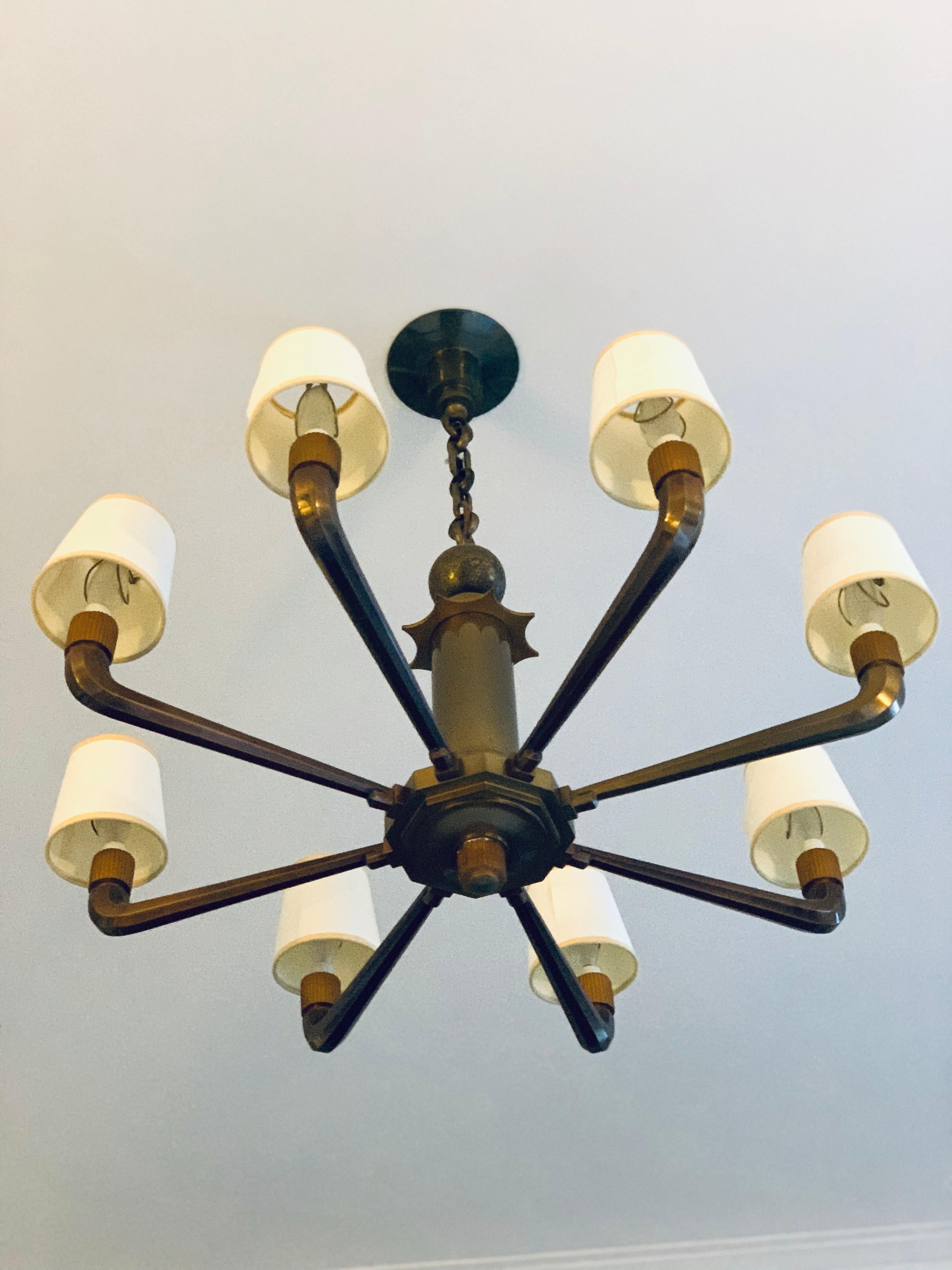 This light came out of a bank in France and is probably early 1920s-1930s. A solid bronze stem leads up to a star and ball detail. This chandelier is solid brass and quite heavy. A very special piece. Looks equally handsome with or without shades.