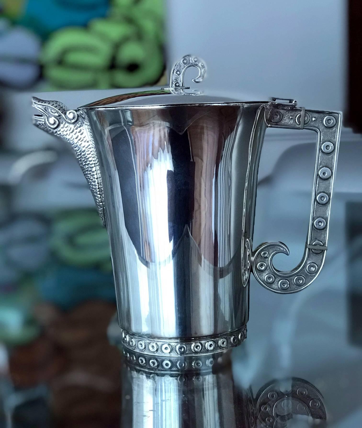 Modern sterling silver pitcher designed and crafted by Tane Orfebres in Mexico. The pitch is decorated with features of the mythical Quetzalcoatl design on the handle, base and lid and highlighted with a dragon sprout.
Hallmarked to the interior of