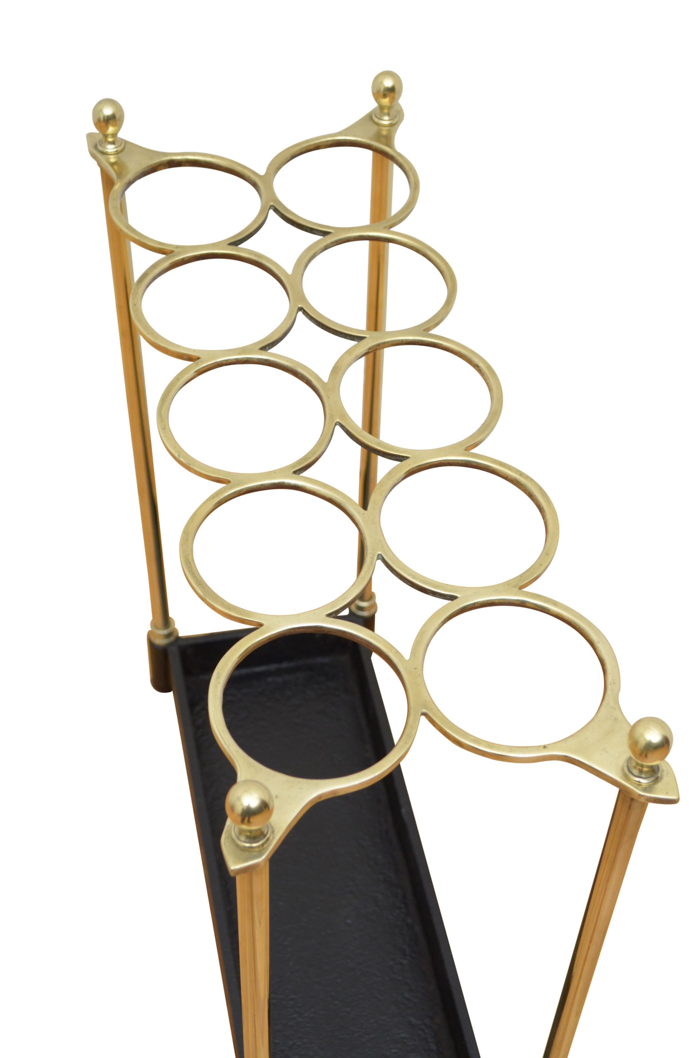 P0247  Exceptional 19th century brass umbrella stand / walking stick stand of large form, having ten circular divisions flanked by decorative finials and cast iron drip tray. This antique umbrella stand has been cleaned and polished and is in home