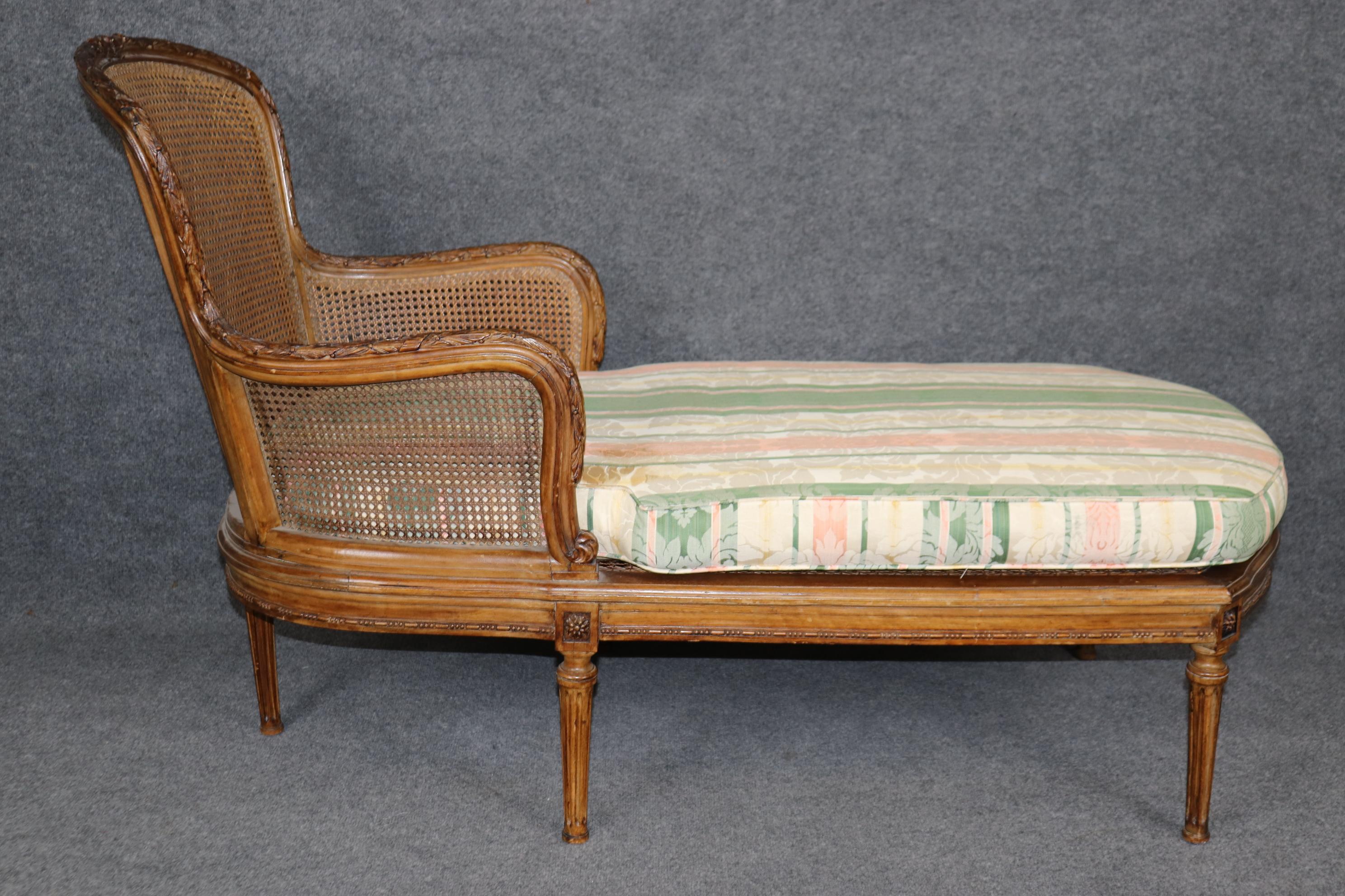 This is a gorgeous and very uniquely designed daybed or chaise. The chaise features a caned back and gorgeous lively damask upholstery above the caned bench seat. The frame is beautifully carved and will show signs of loss to cane holes here and