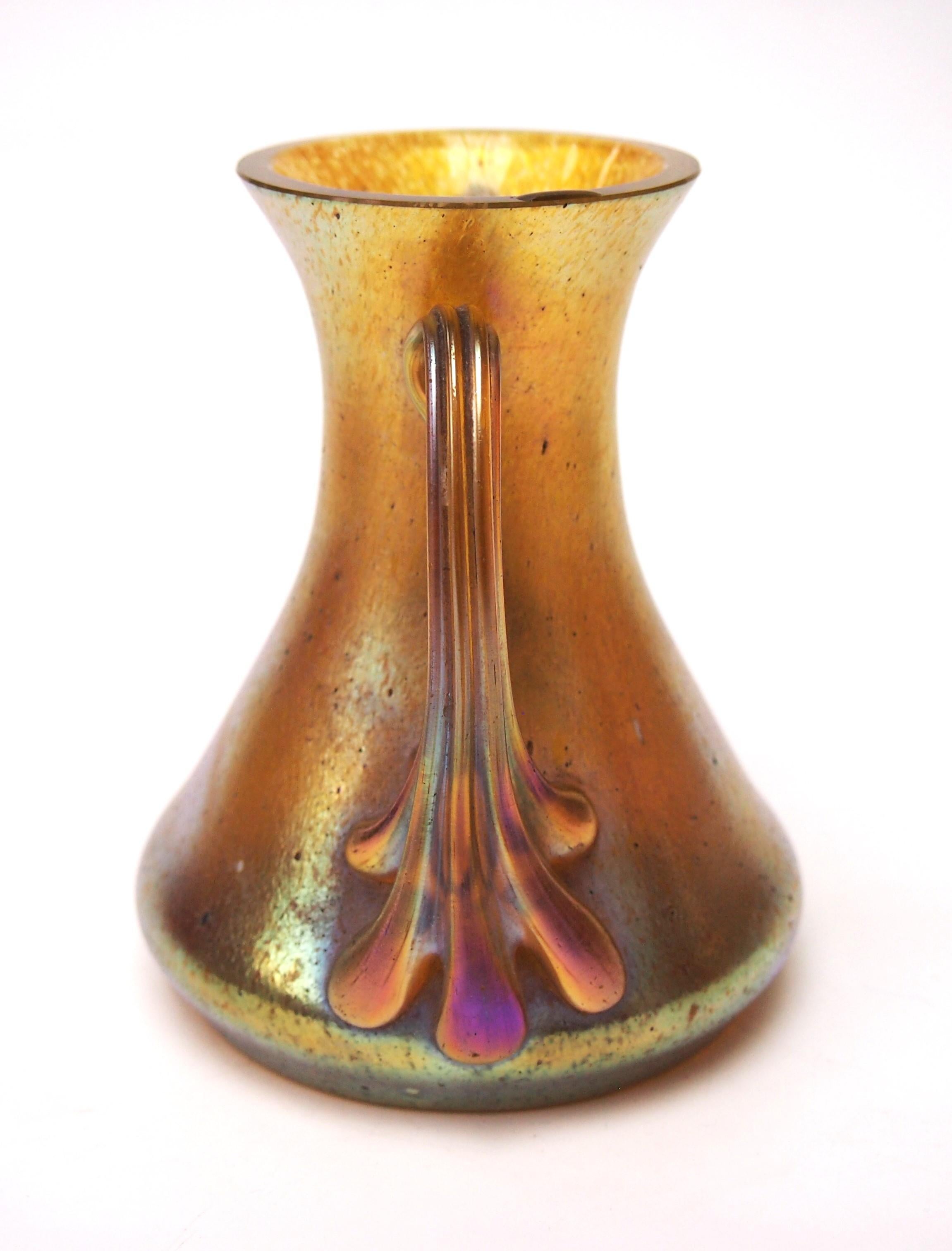 Un favoloso vaso Art Nouveau di Candia Silberiris con manici curvi che terminano con cinque zampe. La finitura Candia Silberiris fa apparire l'intero vaso dorato. Silberiris è uno dei modelli Loetz più antichi e piuttosto insoliti e spesso veniva
