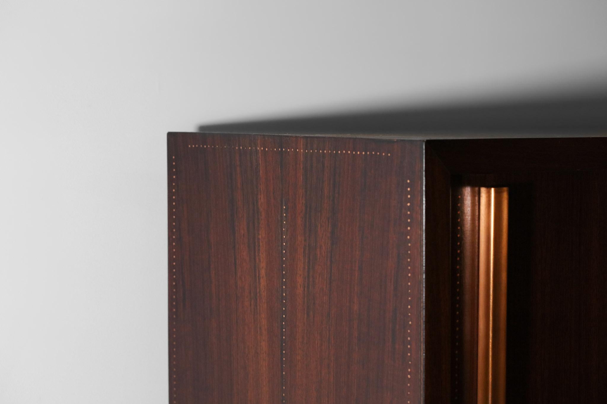 Armoire, bookcase from the 50's by the french designer André Sornay. Structure in solid mahogany and veneer highlighted by a system of brass nails perfectly aligned around the furniture (see photos). The large sliding door opens on a series of solid