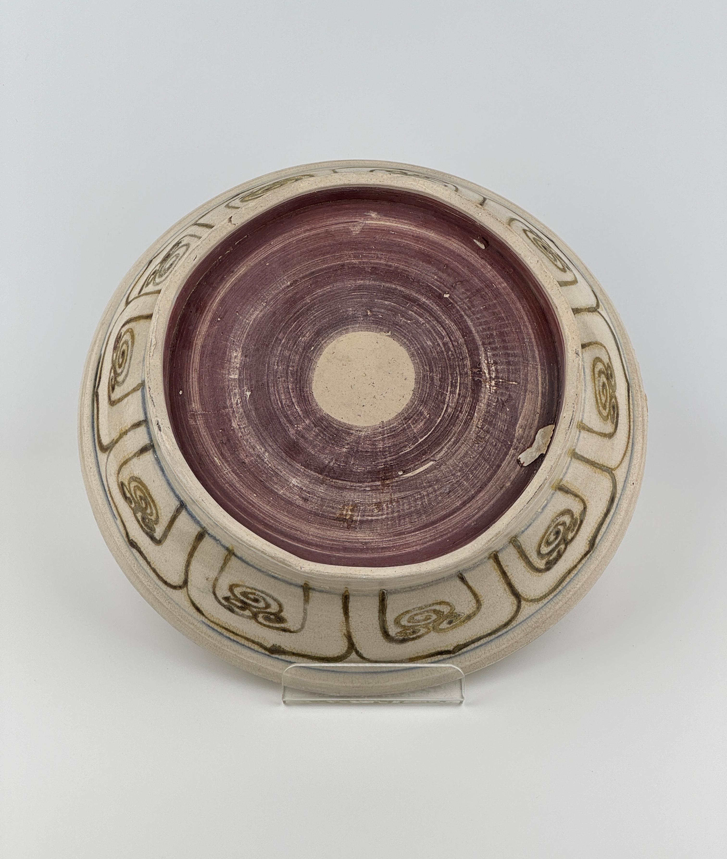 A rare brown colored stoneware dish with a central floral motif, likely a lotus, which is a recurrent symbol in Asian art representing purity and beauty. The design's fluidity and organic shapes suggest it was painted by a skilled artisan, making it