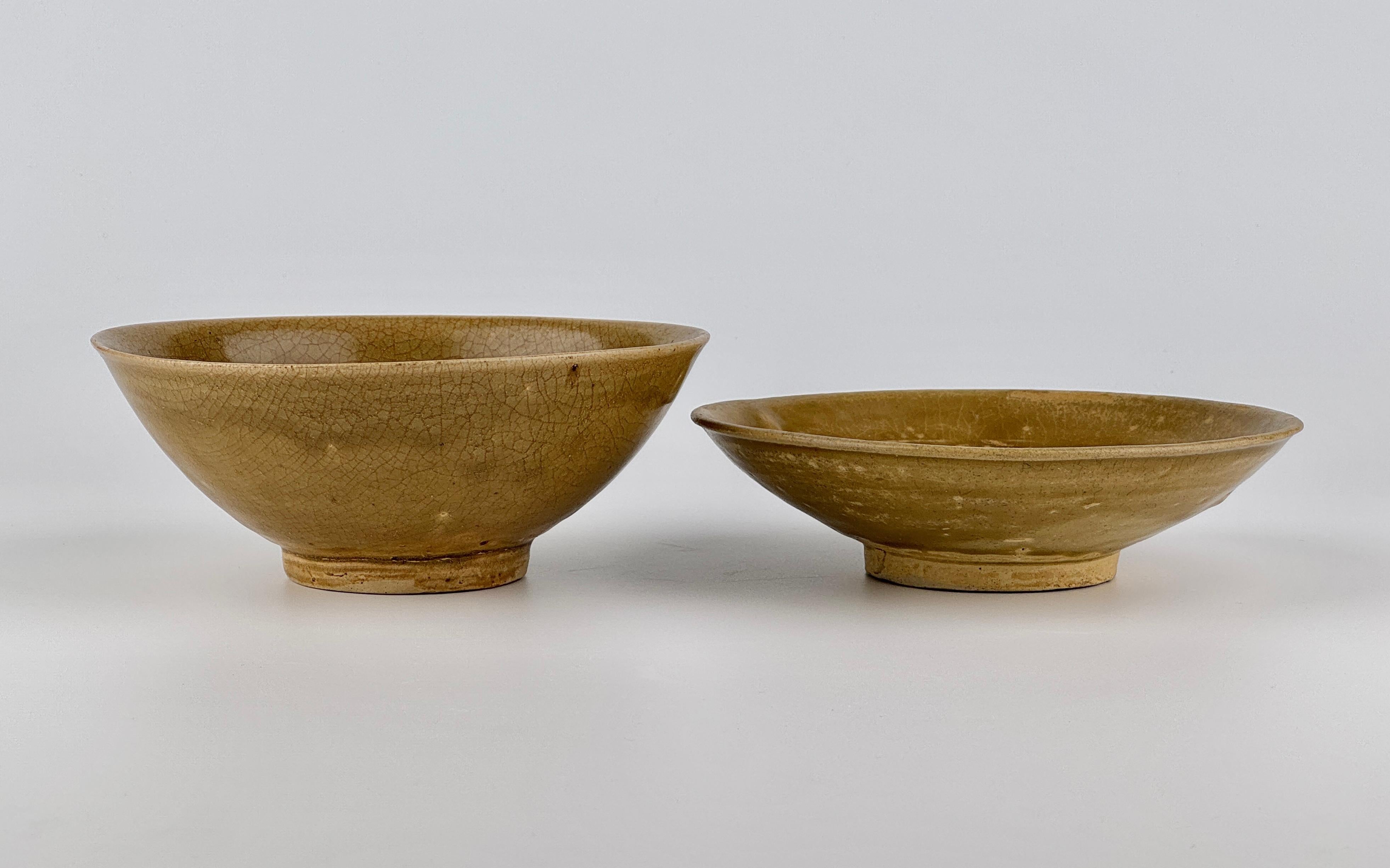 These Vietnamese stoneware bowls have shallow, wide, saucer-like form, crafted from pale beige clay with an olive-green glaze. The interior features a delicately molded design of scrolling lotus foliage, subtly revealed beneath the translucent