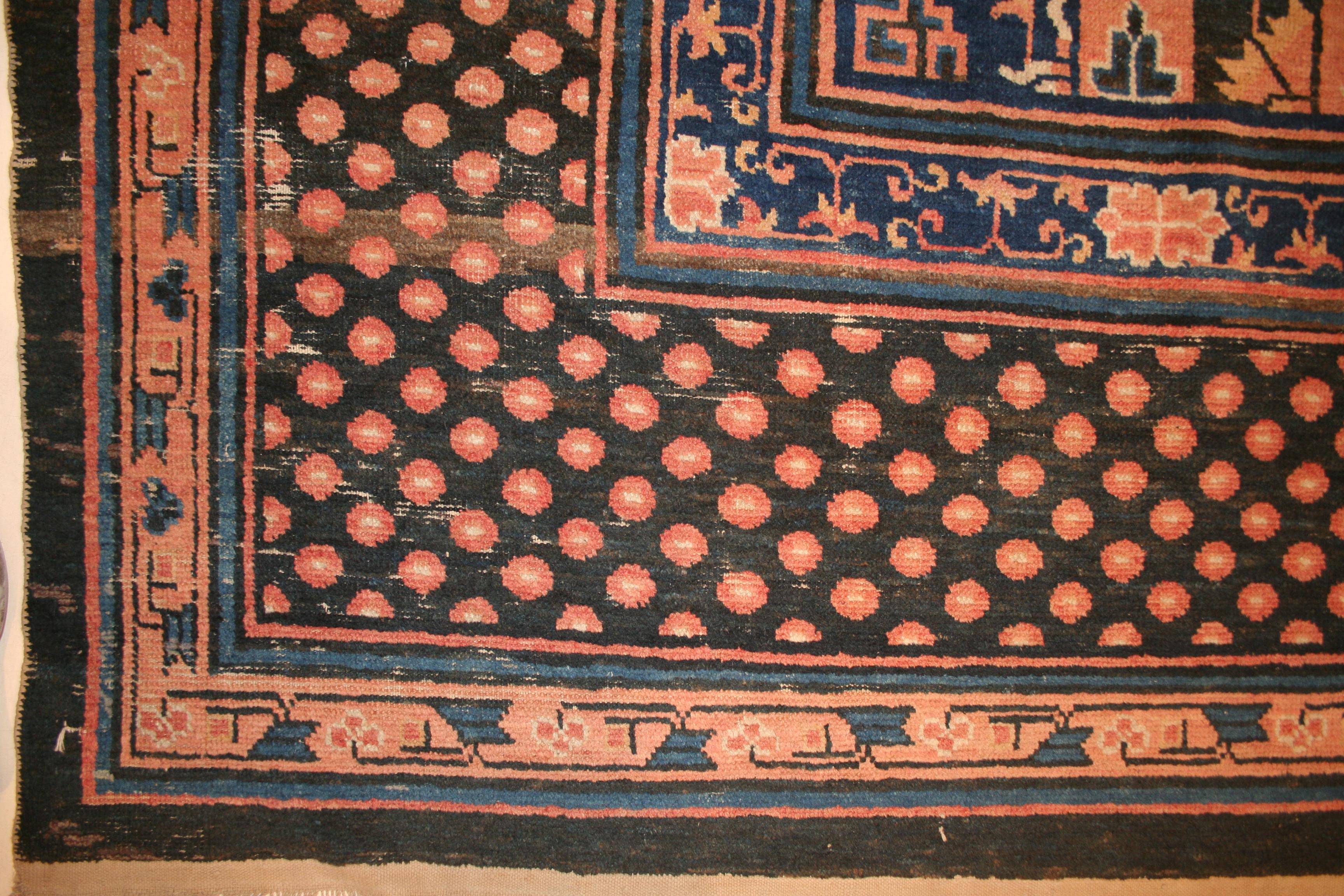 A very rare and elegant oversized Kansu carpet, distinguished by a quincuncial pattern composed by a central Mandala roundel and four quartered elements in the corners, overlaid on a dark blue background embellished by an infinite repeat of small