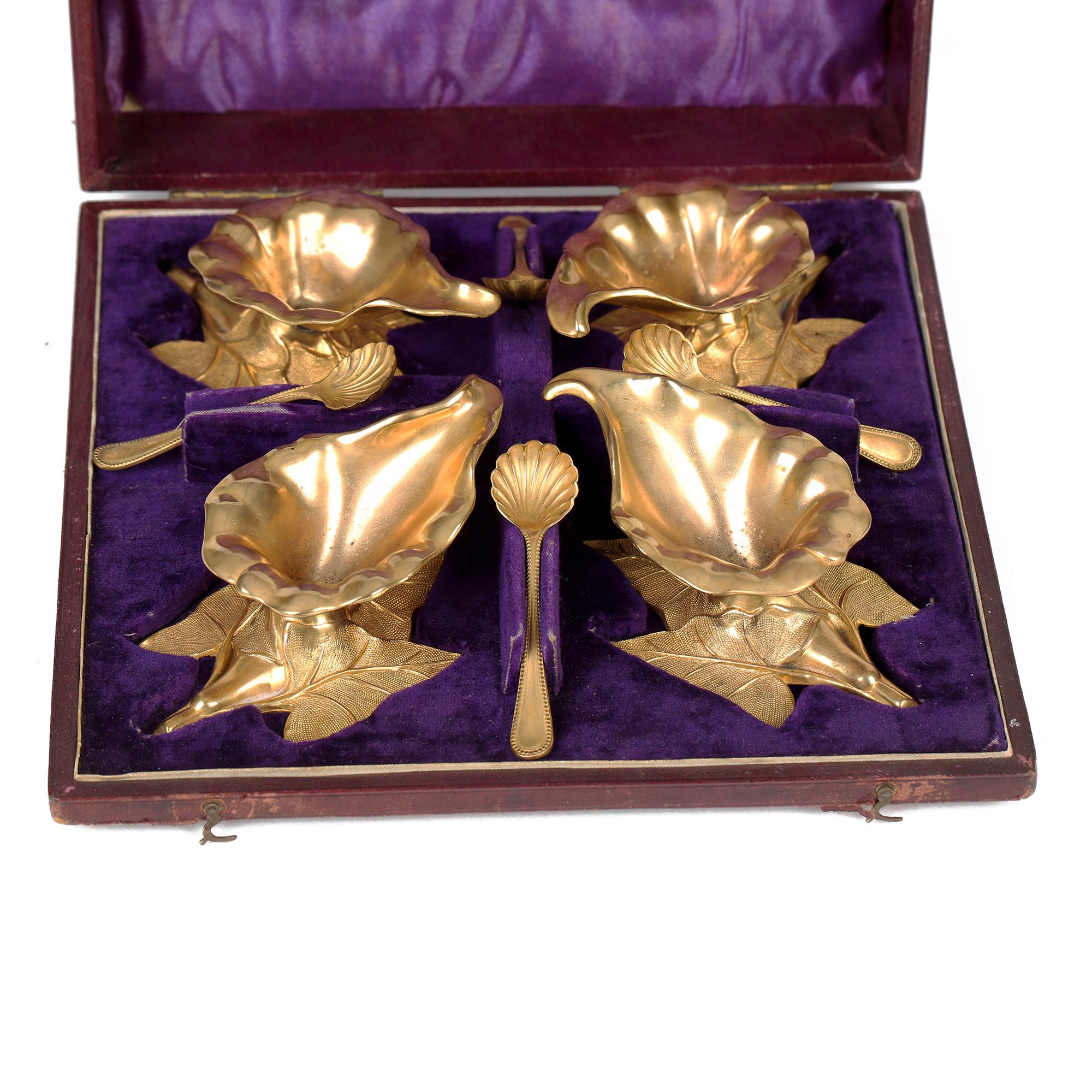 A very rare and unusual British cased set four gilded metal salts and spoons formed as flowerheads dated 1870. The decorative salts are formed as flower heads supported on a three leaf base and are presented in a fitted leather cover case with a