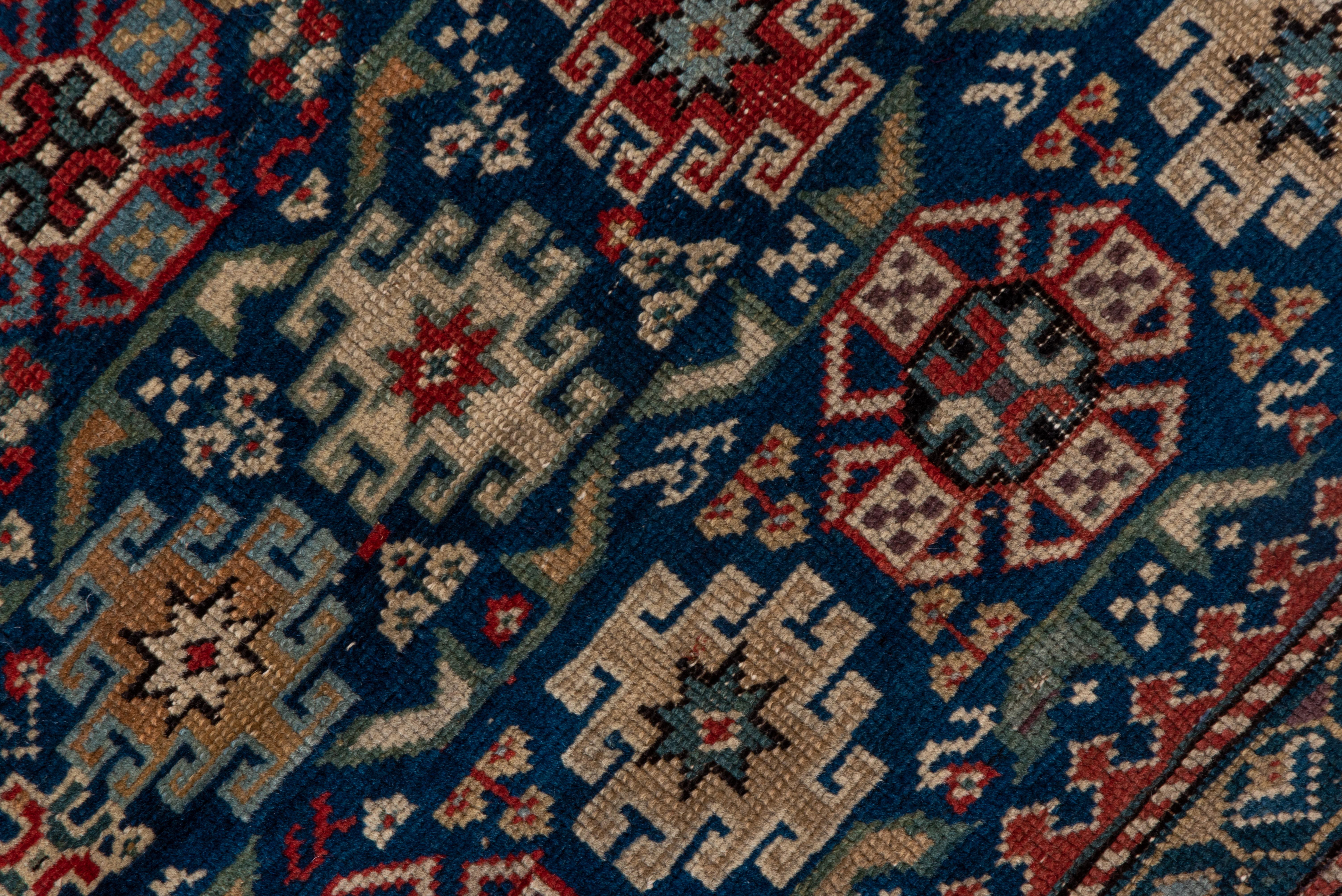 This good condition eastern Caucasian scatter features the characteristic Chichi design of small side-hooked medallions and Maltese crosses on an abrashed royal blue ground, with a classic rosette and diagonal bar main border on a brown-black