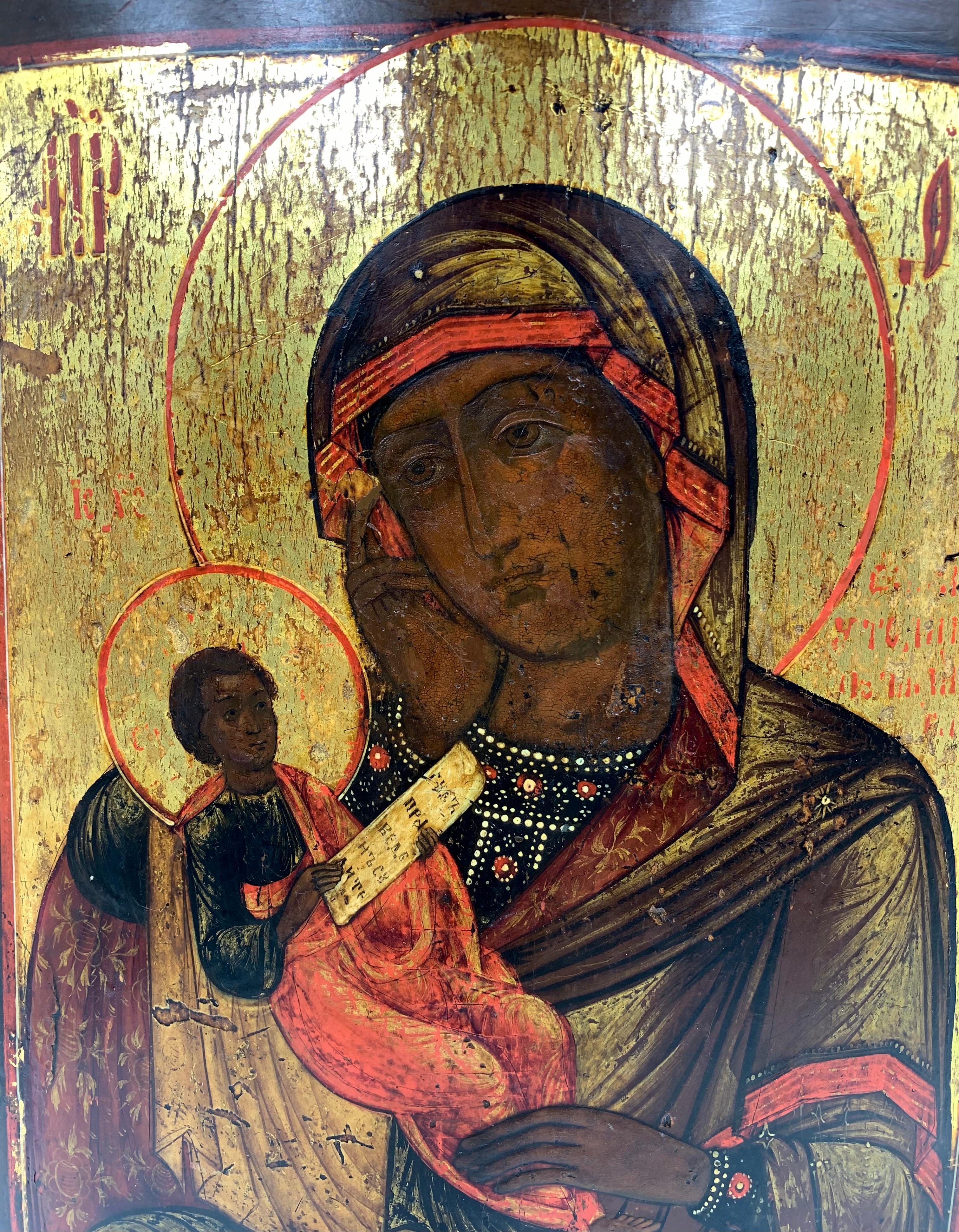 Seldom seen antique Russian icon, tempera and gold on wooden panel, of the Black Madonna, 19th century.
The Mother of God depicted holding the infant Jesus, who, in turn, holds a scroll written in old Cyrillic. Her right hand is raised to her