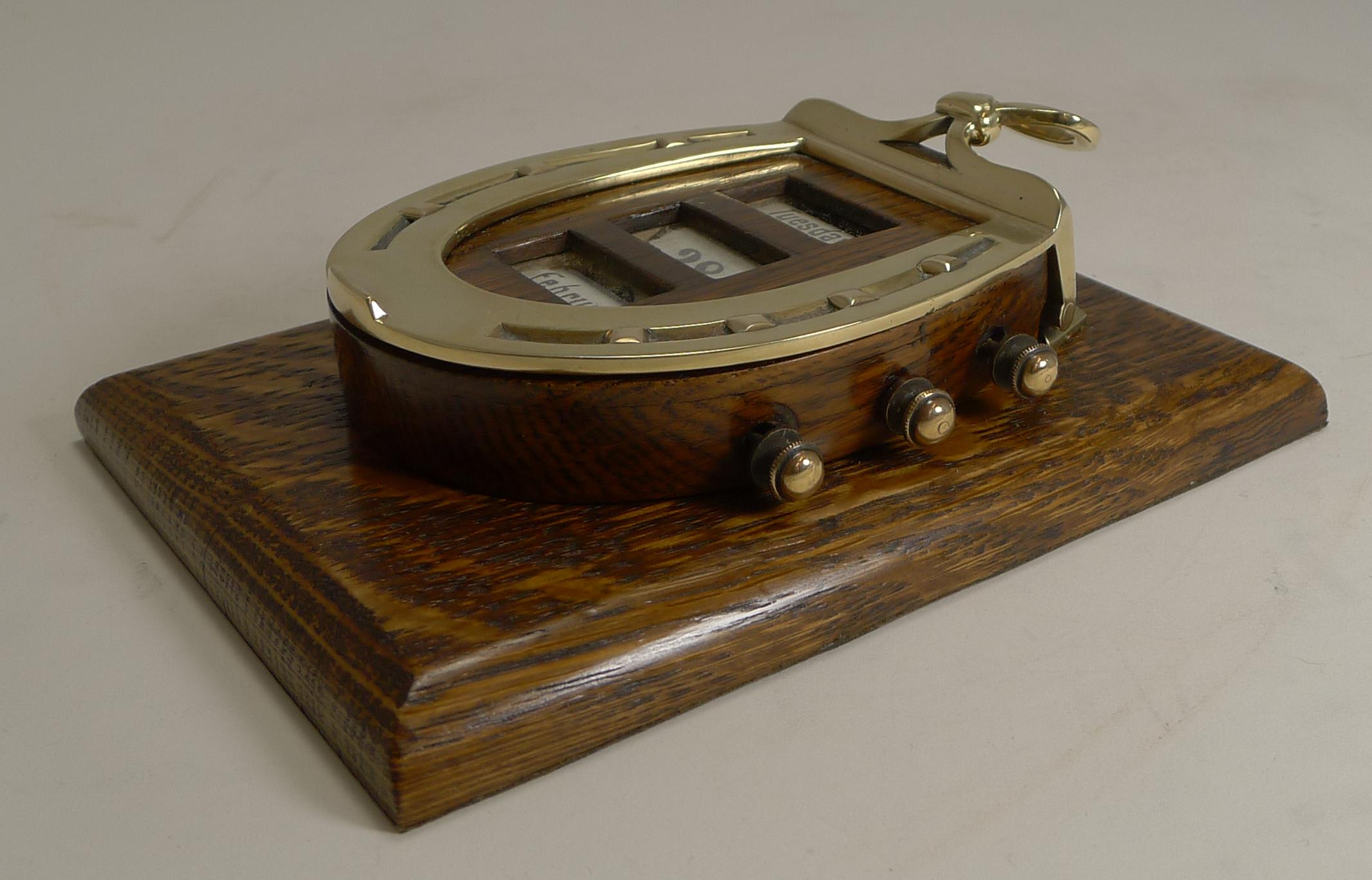 A magnificent find, I absolutely adore this gem, something I have never seen before.

Made from solid English oak and polished brass, this desk-top paper or letter clip incorporates a horseshoe shaped perpetual calendar with the brass knobs to