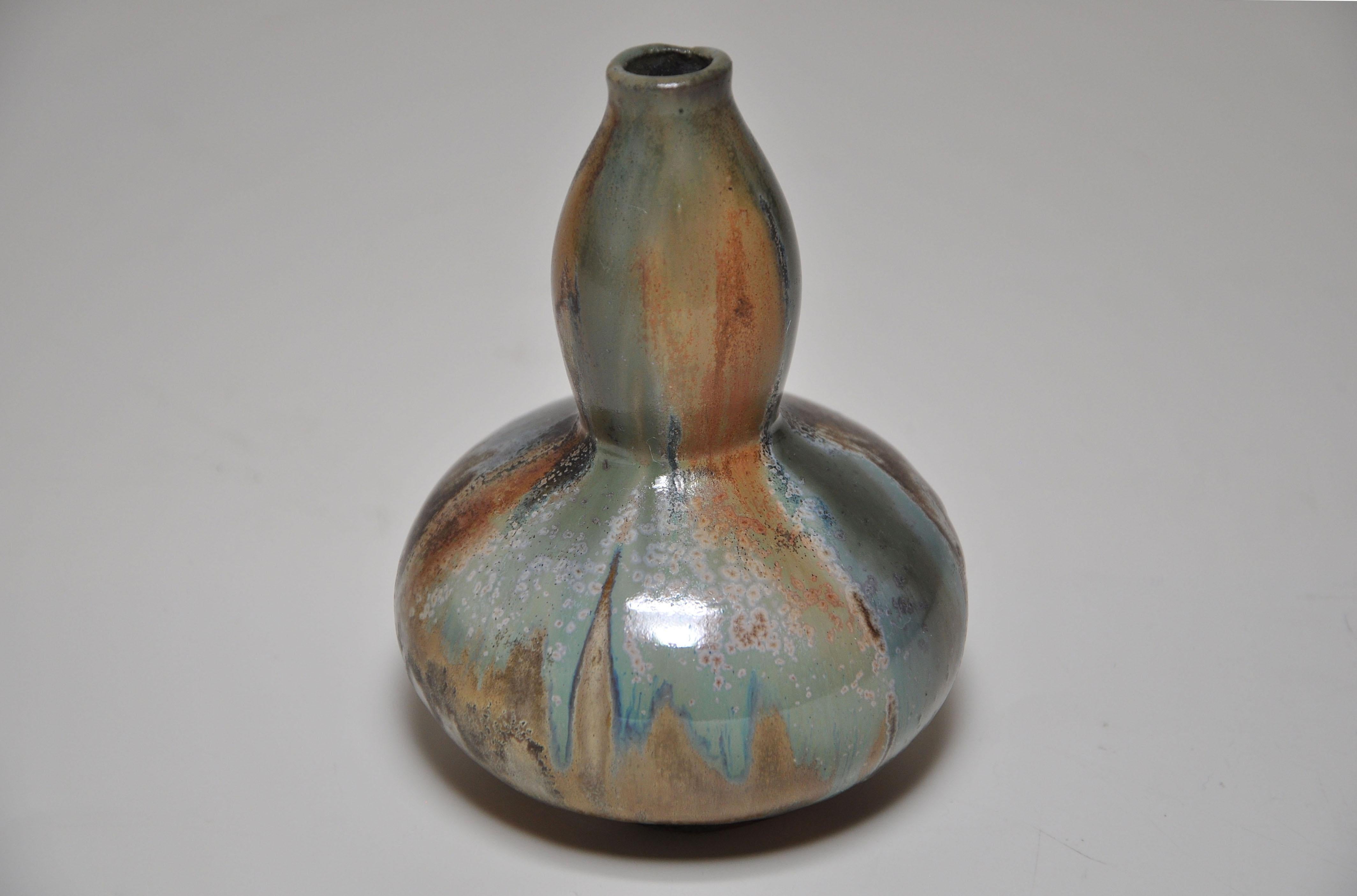 Eine seltene kleine Vase aus Steinzeug mit doppelter Kalebasse in japonistischer Form, am oberen Rand frei bearbeitet. Sie hat eine dicke braune, grün ockerfarbene, fließende Flammglasur. Von dem französischen Kunstkeramiker Jean Langlade
