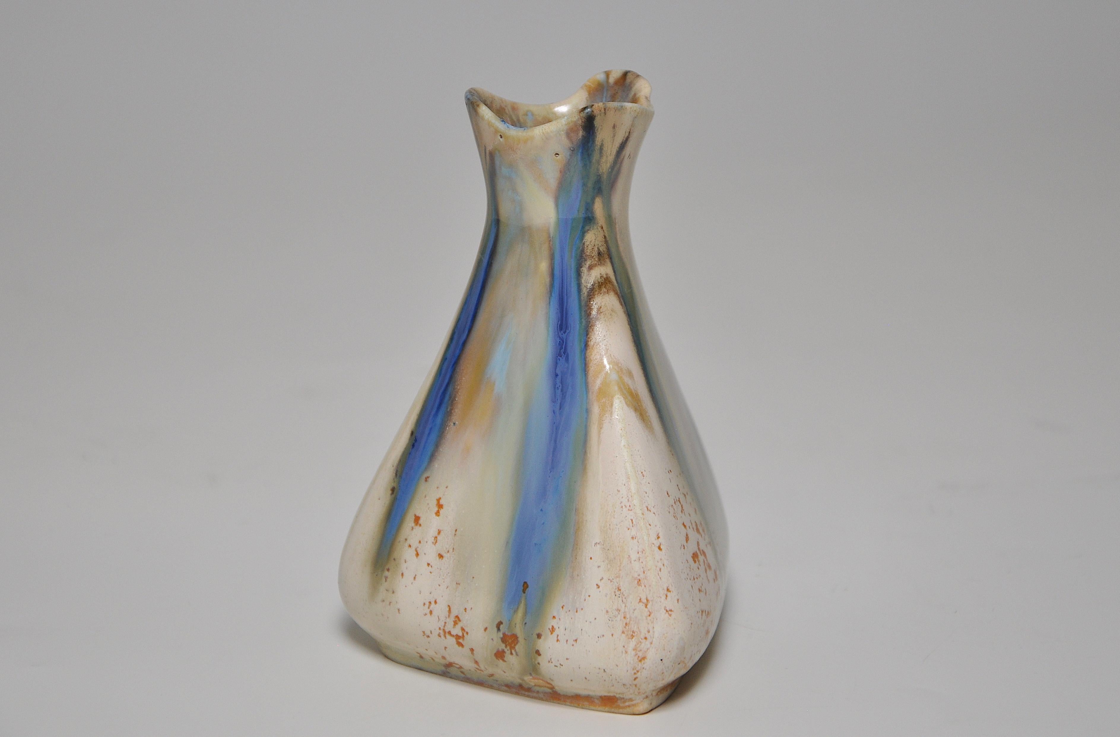 A perfect example of a small stoneware vase of Japoniste inspiration, triangular in form with an flared top, and covered with a flowing cream, green, and blue flame glaze, flecked with brown. By the French art ceramist Jean Longlade (1879-1928) of