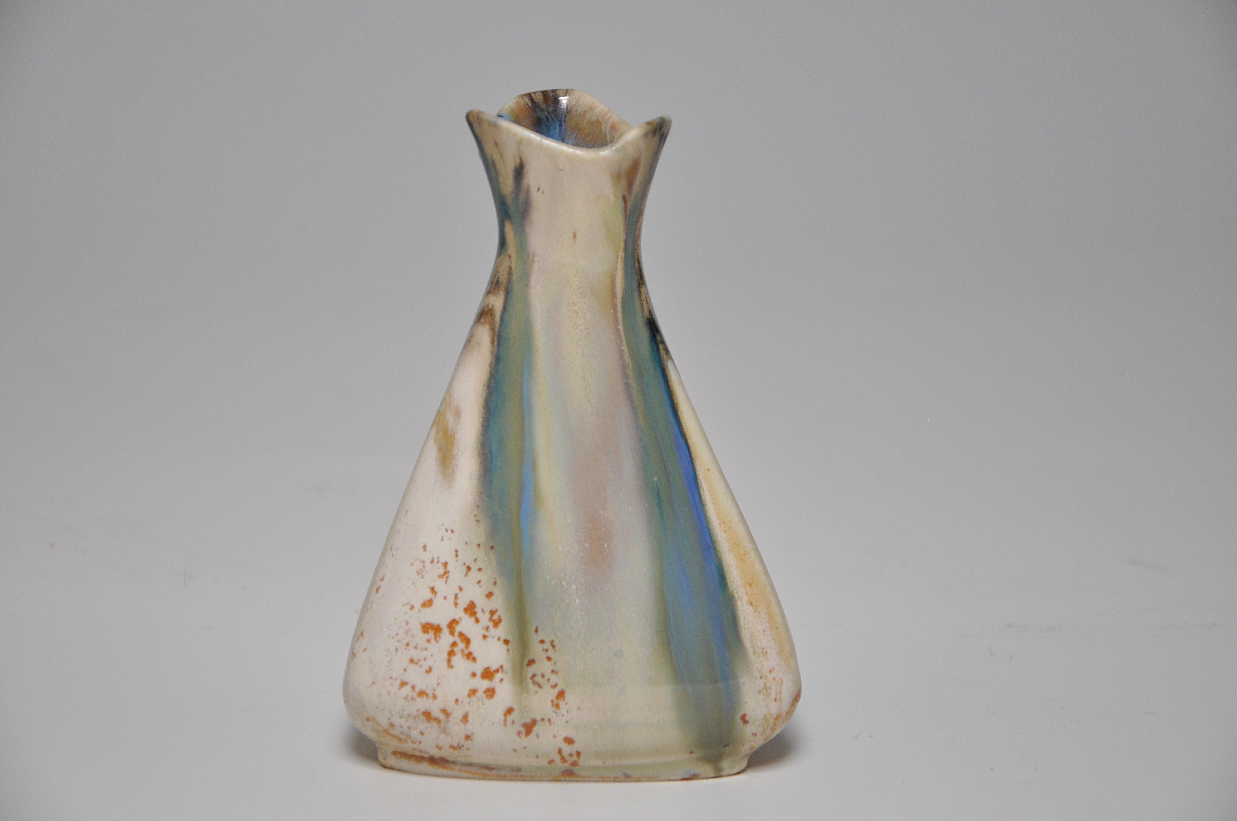 A perfect example of a small stoneware vase of Japoniste inspiration, triangular in form with an flared top, and covered with a flowing cream, green, and blue flame glaze, flecked with brown. By the French art ceramist Jean Longlade (1879-1928) of