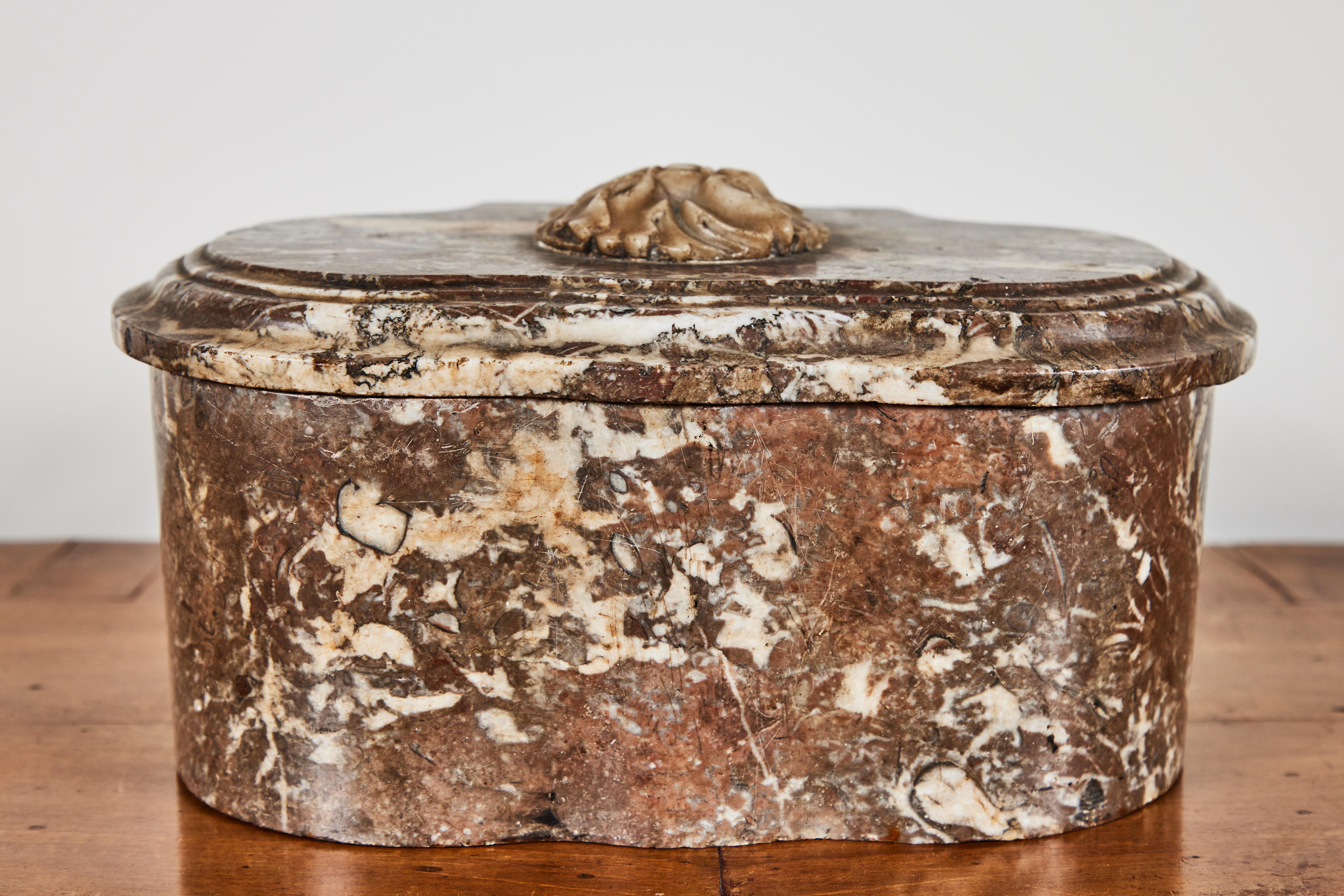 Elegant, bow front, lift top, hand carved marble box with two, round compartments. The sinuous base is mirrored in the stepped, overhanging top which is surmounted by a relief carved flower.