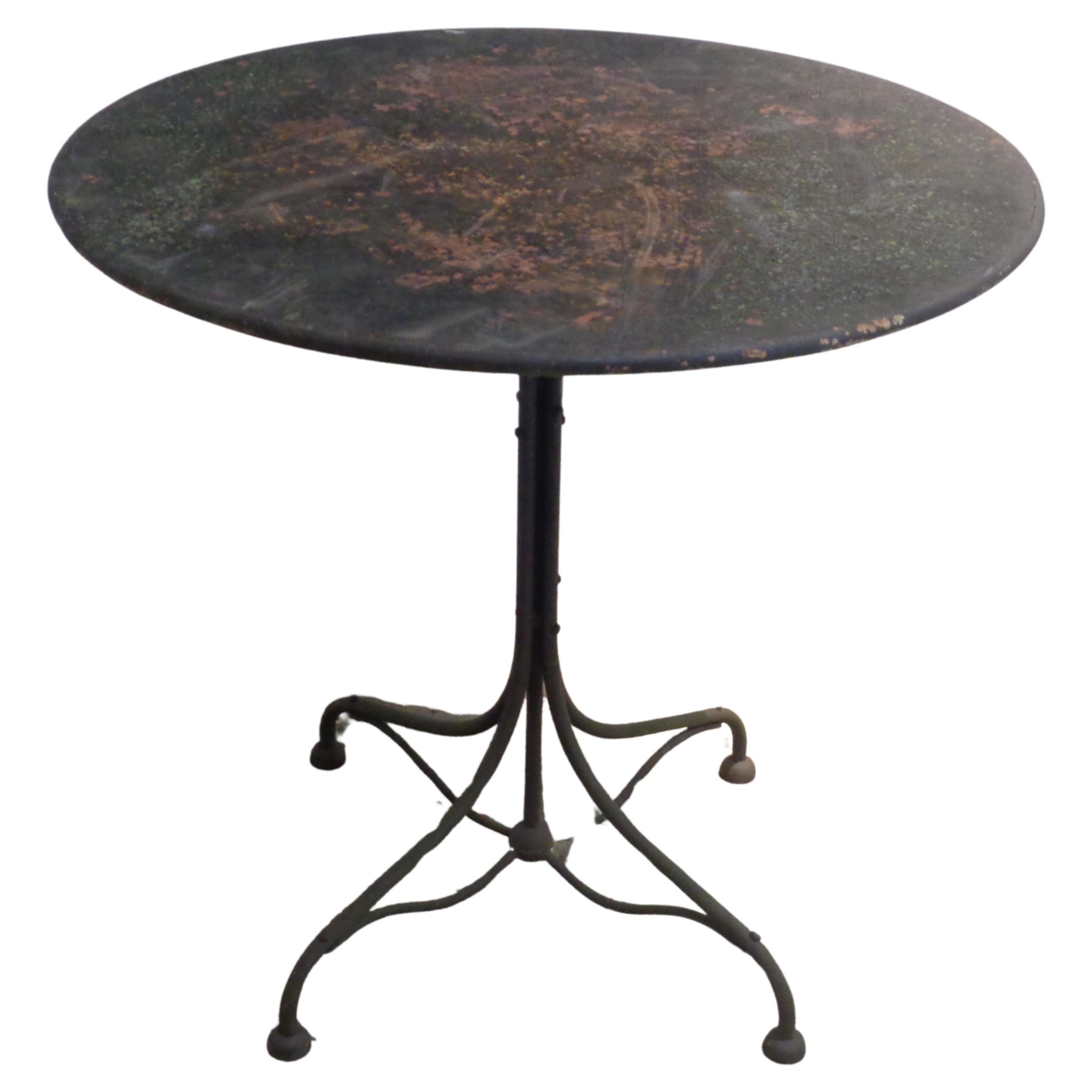 Antique French three piece iron bistro set in nicely aged old black painted surface showing underlying layers of earlier paint colors. The bistro table w/ circular steel top and a great looking sculptural iron base. The two chairs w/ very fine hand