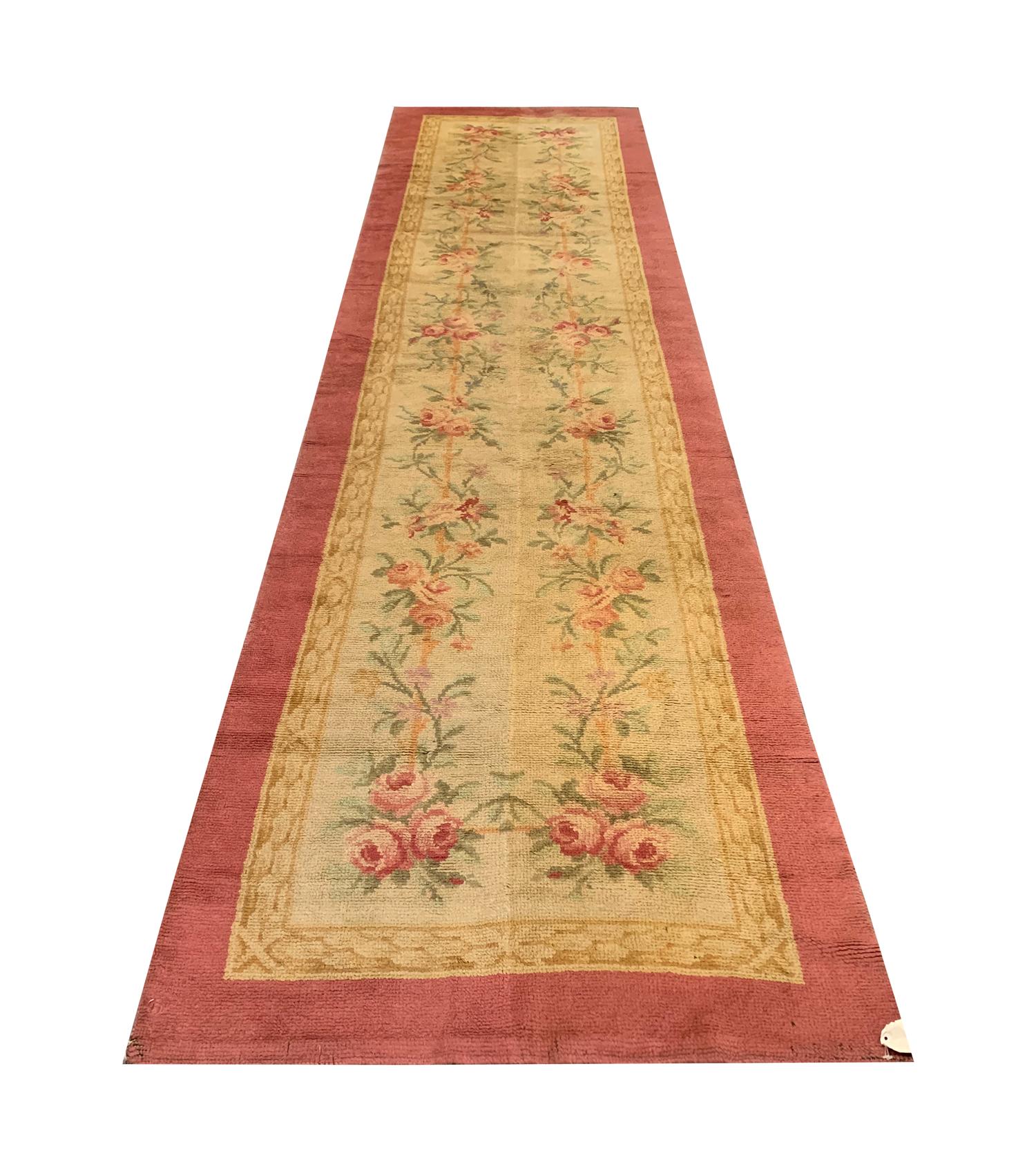 This fine wool runner rug is an antique Savonnerie. Woven by hand in the French Savonnerie manufacturer, prestigious European rug manufacturers, with only the finest materials. The design features an elegant scrolling flower design woven in accents