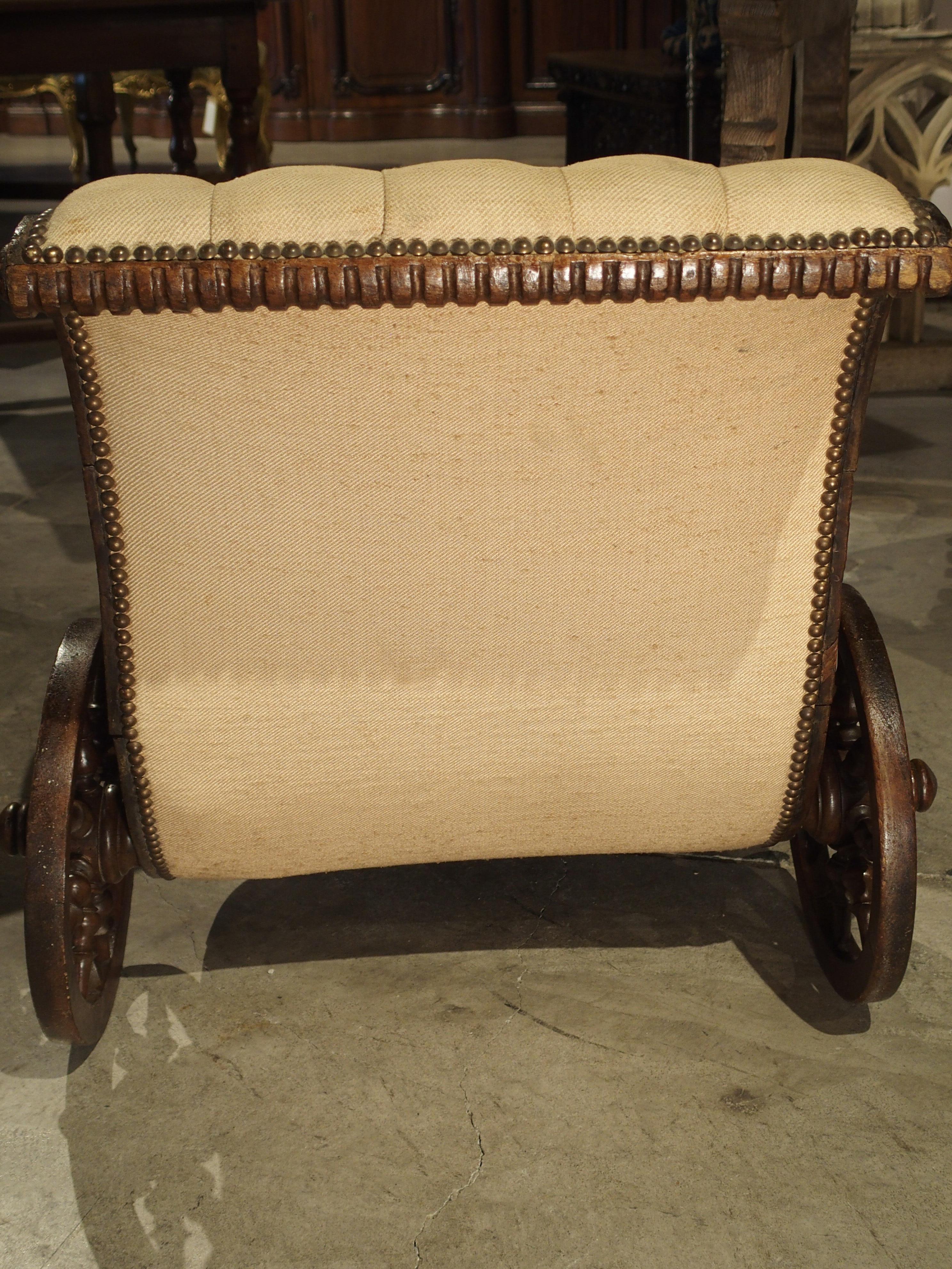 This charming antique wooden children’s carriage was made in the last half of the 1800s. It is a completely unique decorative piece and has been carved from walnut wood. It has tufted upholstery held in by brass nailheads, and the wooden rims,
