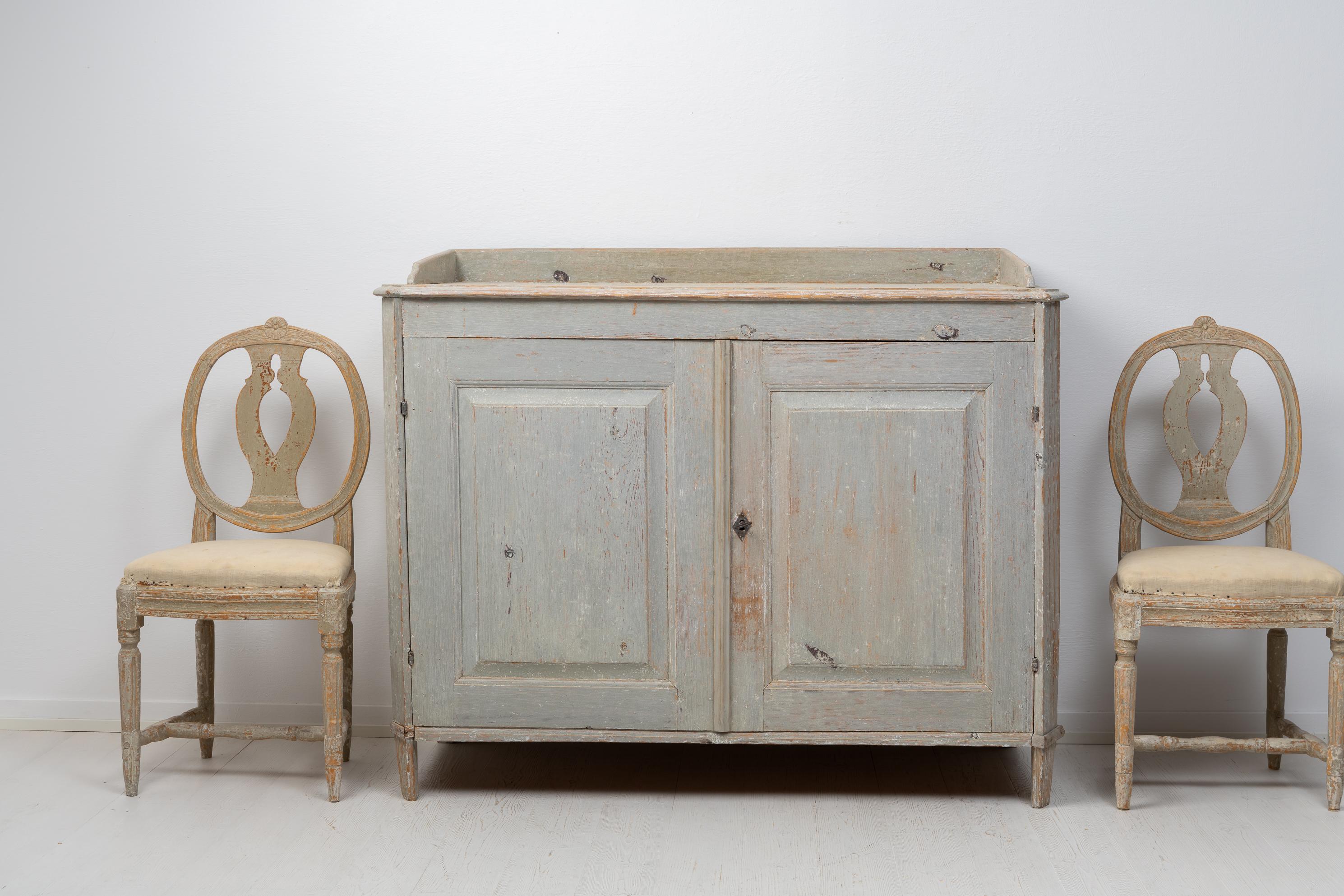 Rare antique gustavian sideboard from Northern Sweden made around 1780. The sideboard is made in painted pine and dry scraped by hand down to the original first layer of paint from the late 1700s. It has two doors and an interior with shelves. The