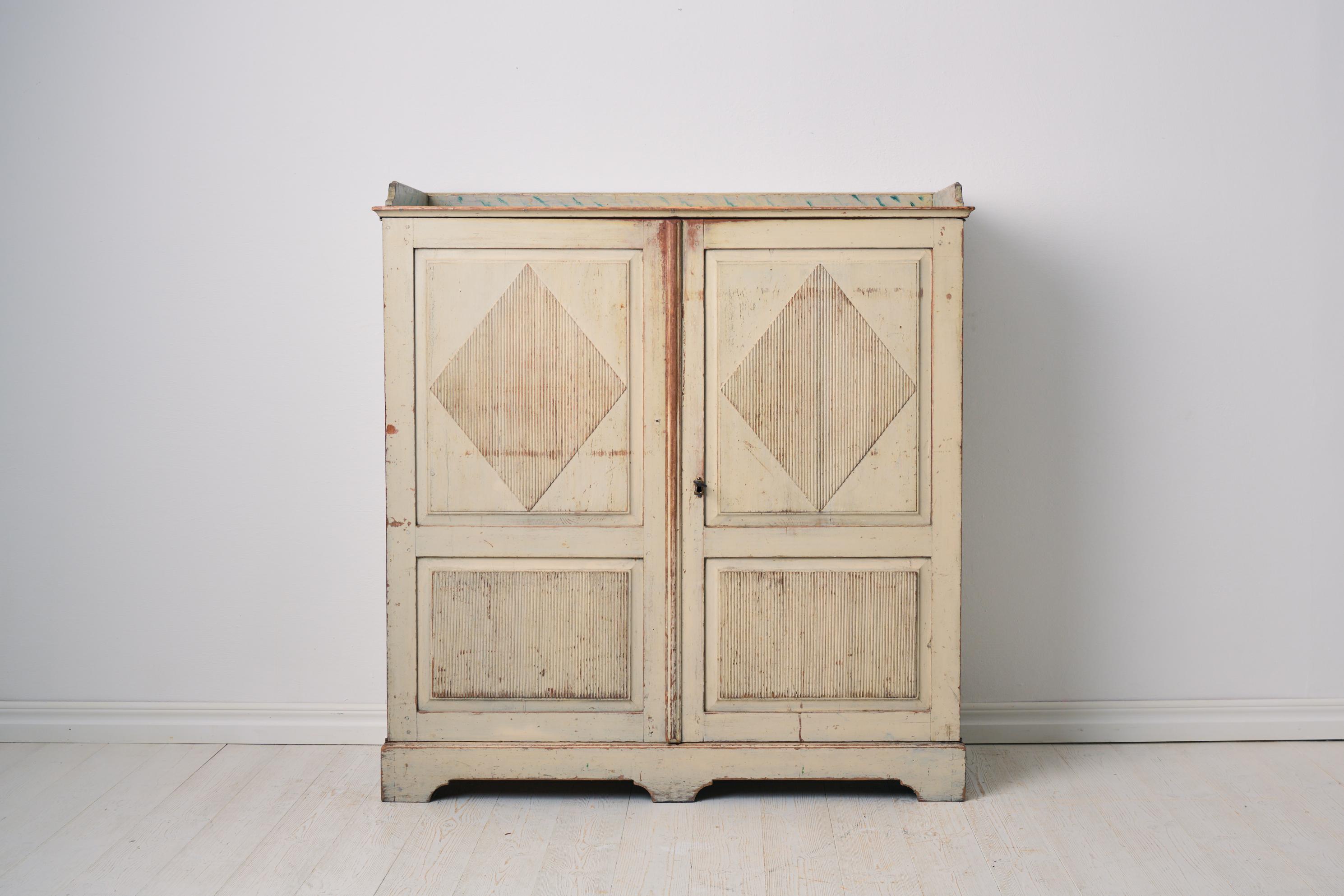 Rara credenza antica autentica proveniente dalla Svezia. La credenza è un mobile da casa in stile gustaviano proveniente dalla Svezia settentrionale. Realizzata a mano in pino massiccio con doppie ante con un classico decoro gustaviano a forma di