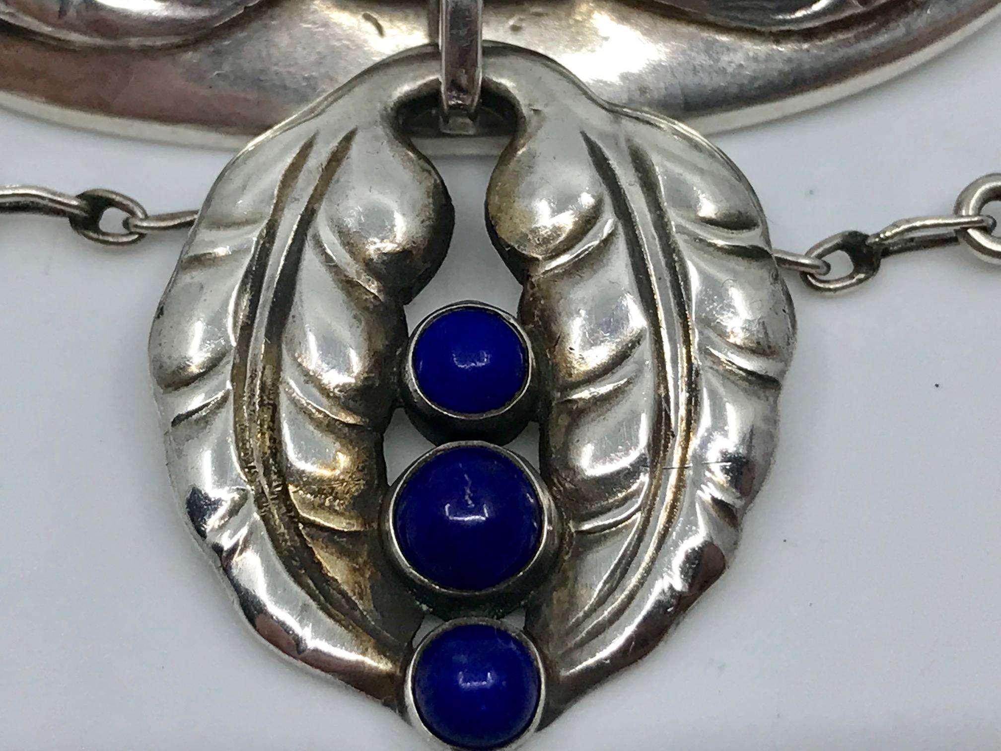 This is a rare antique Georg Jensen silver brooch with seven cabochon set lapis lazuli stones, design #26 by Georg Jensen.
Measures 2½” x 3″ (6.4cm x 7.6cm).
Antique Georg Jensen hallmarks from 1908-1914, 828s.