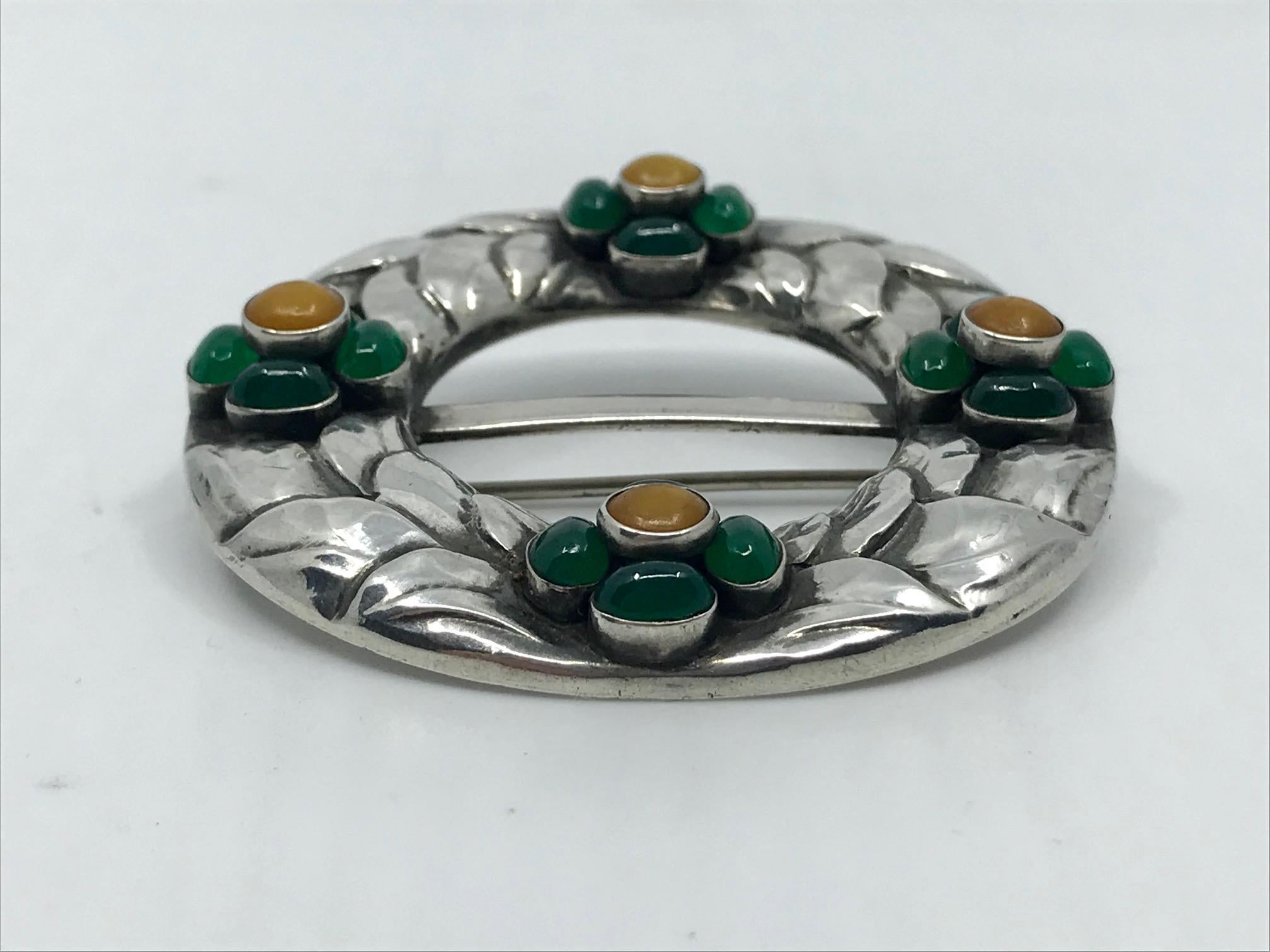 This is a rarely seen antique Georg Jensen silver brooch with cabochon set amber and green agate stones, design #4 by Georg Jensen.
Measures 2 1/8″ (5.4cm) in diameter.
Antique Georg Jensen hallmarks from 1908-1914, 826s.